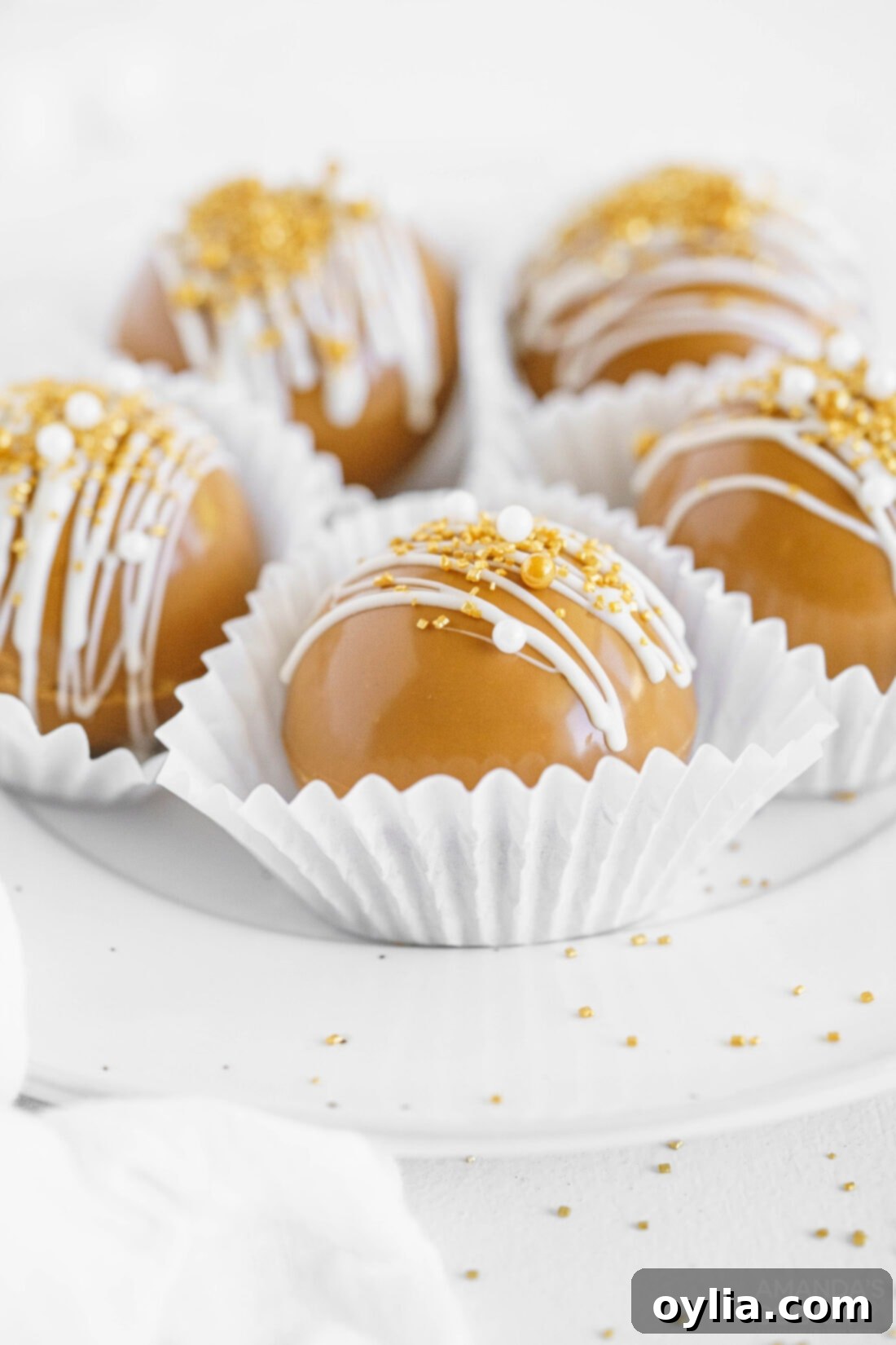 Collection of caramel hot cocoa bombs neatly arranged in white paper liners, ready for gifting or serving.