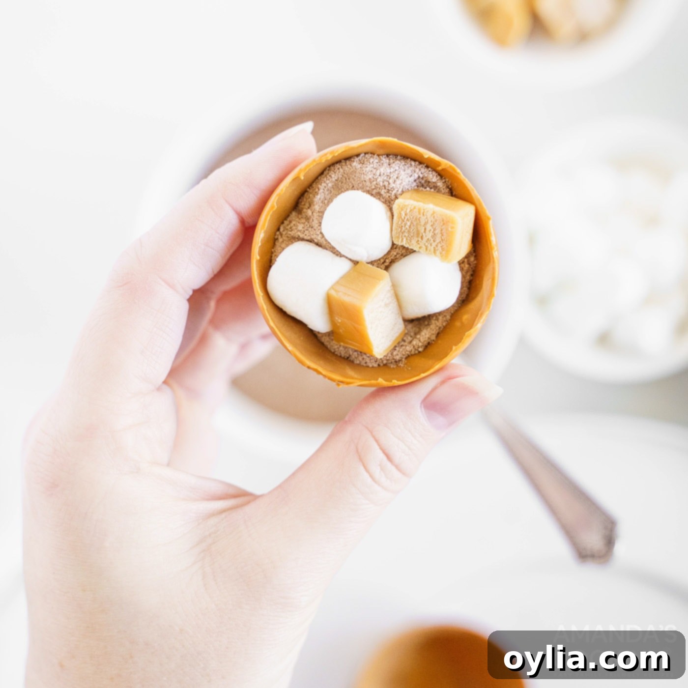 A half-sphere of caramel candy filled with hot cocoa powder and mini marshmallows, ready for the other half.