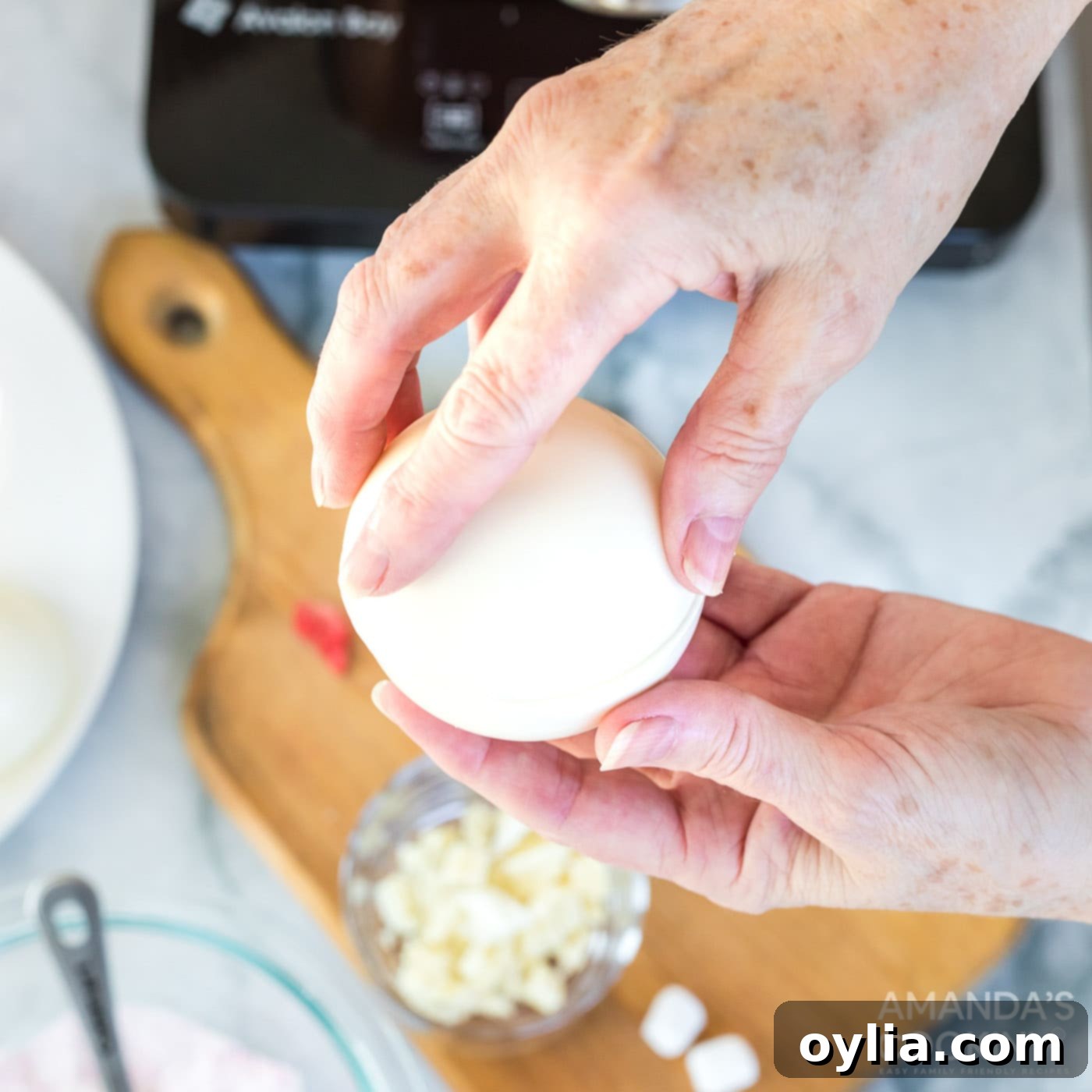 Sealing the two halves of a white chocolate hot cocoa bomb together, creating a perfect sphere.