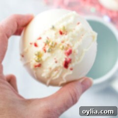 Indulgent Strawberry White Chocolate Hot Cocoa Bombs 17 Finished Strawberry White Chocolate Hot Cocoa Bombs, garnished with decorative drizzles and sprinkles.