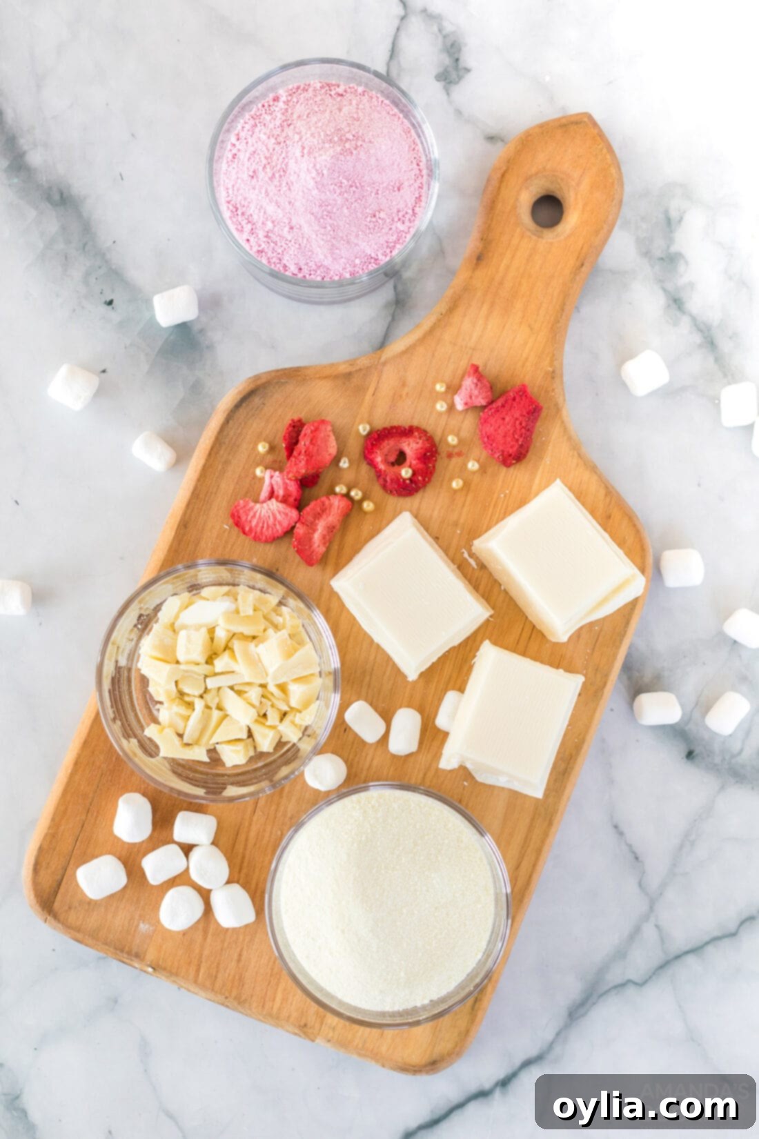 Indulgent Strawberry White Chocolate Hot Cocoa Bombs 4 All the ingredients neatly laid out for making white chocolate strawberry hot cocoa bombs, including white chocolate, powdered drink mix, freeze-dried strawberries, and mini marshmallows.