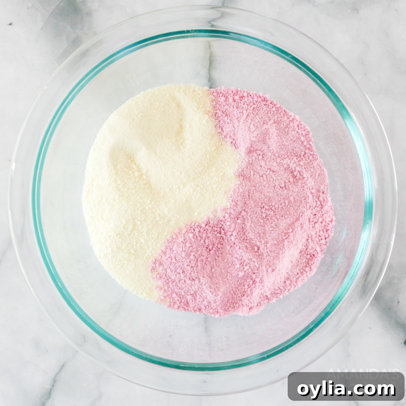 Strawberry powdered drink mix and powdered milk combined in a bowl, ready for the hot cocoa bombs.