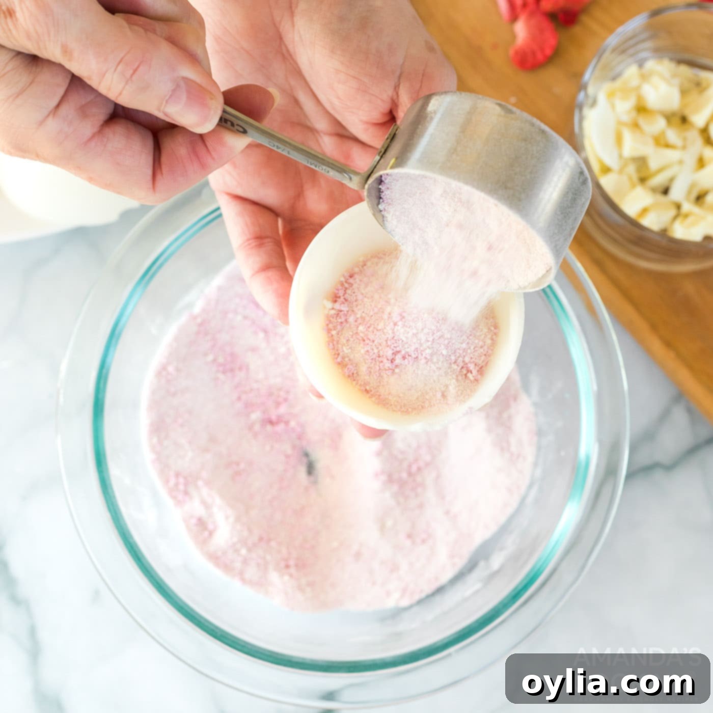 Filling one half of a white chocolate sphere with the strawberry powdered mixture.