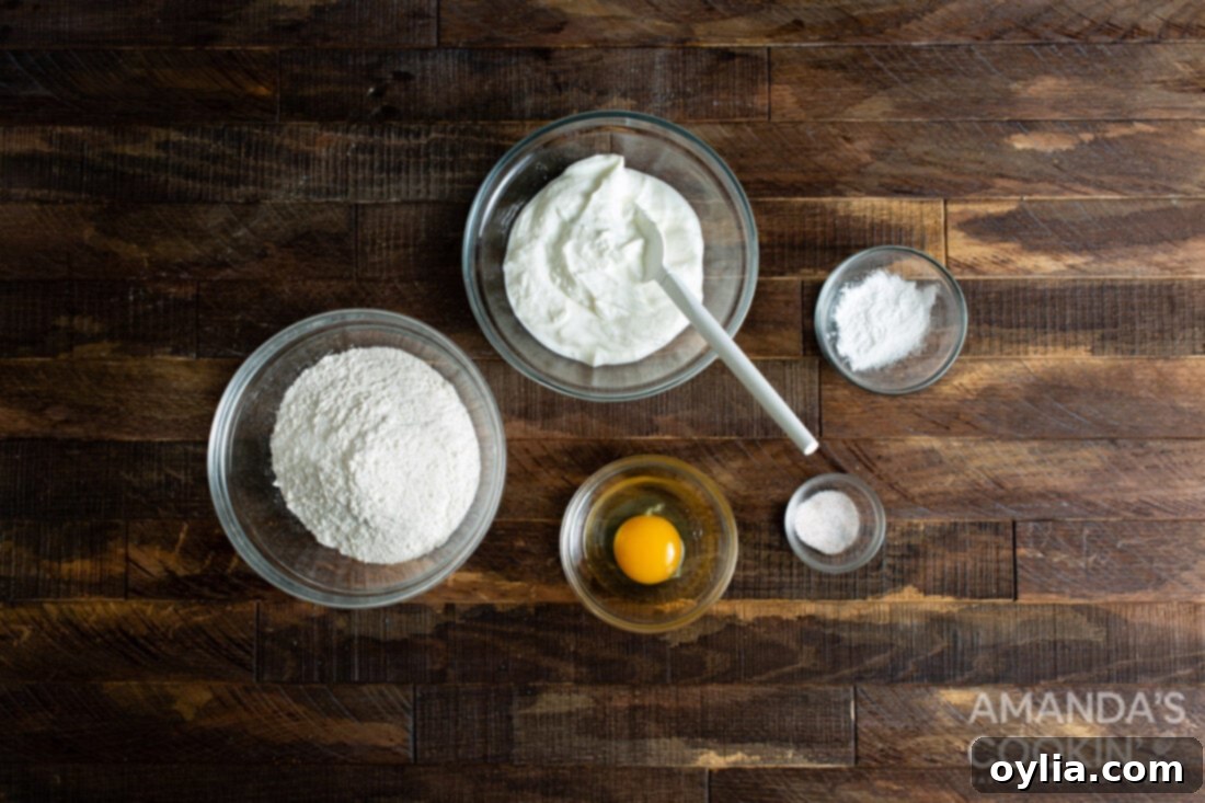 Perfect Air Fryer Bagels 4 A collection of ingredients for making air fryer bagels, including flour, yogurt, and an egg, neatly arranged.