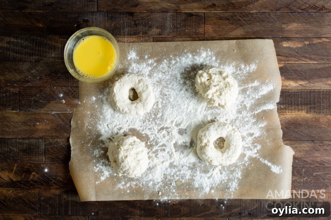 Raw air fryer bagel dough, shaped into patties with center holes, resting on parchment paper.