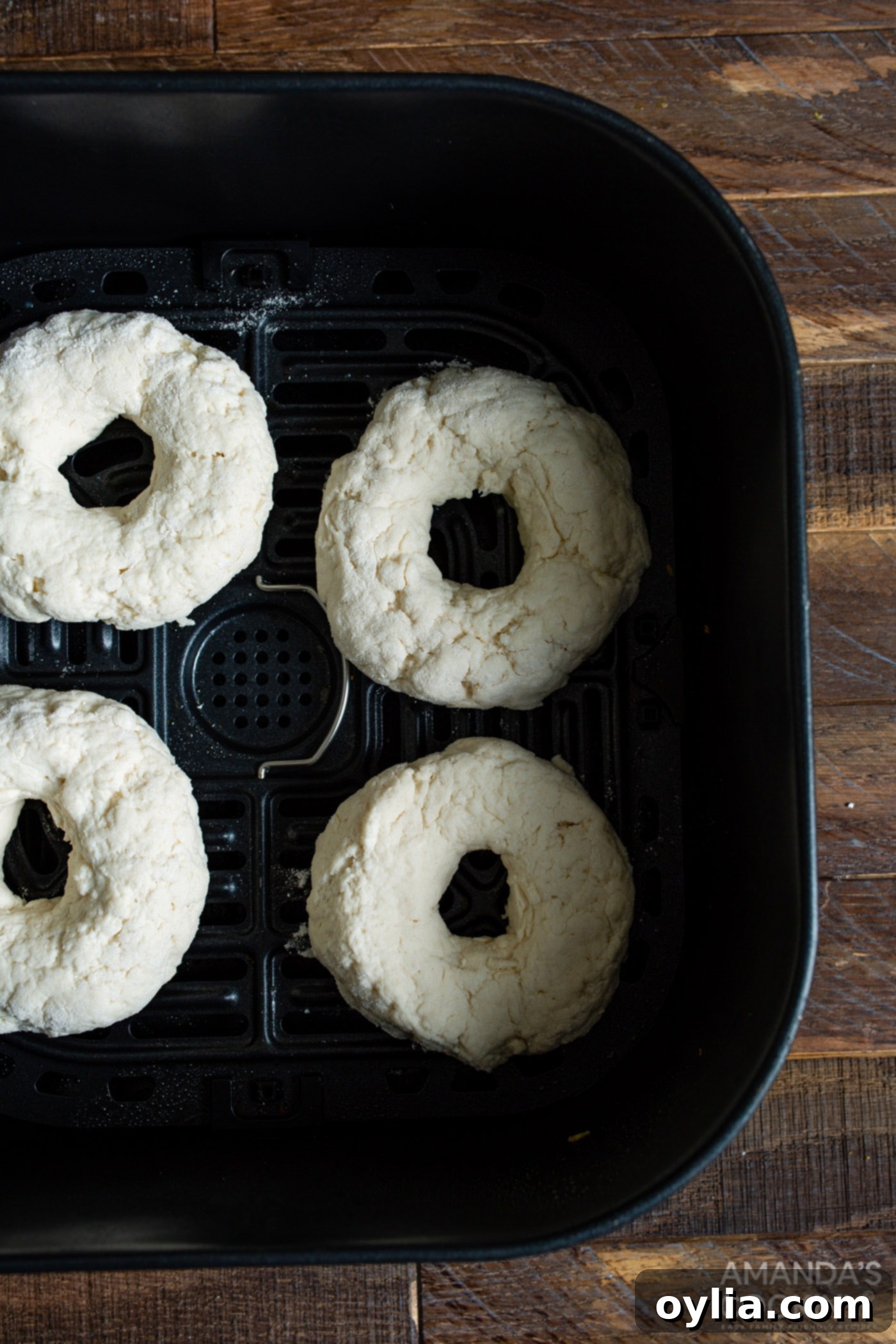 Raw bagel dough pieces placed in an air fryer basket, ready for cooking.