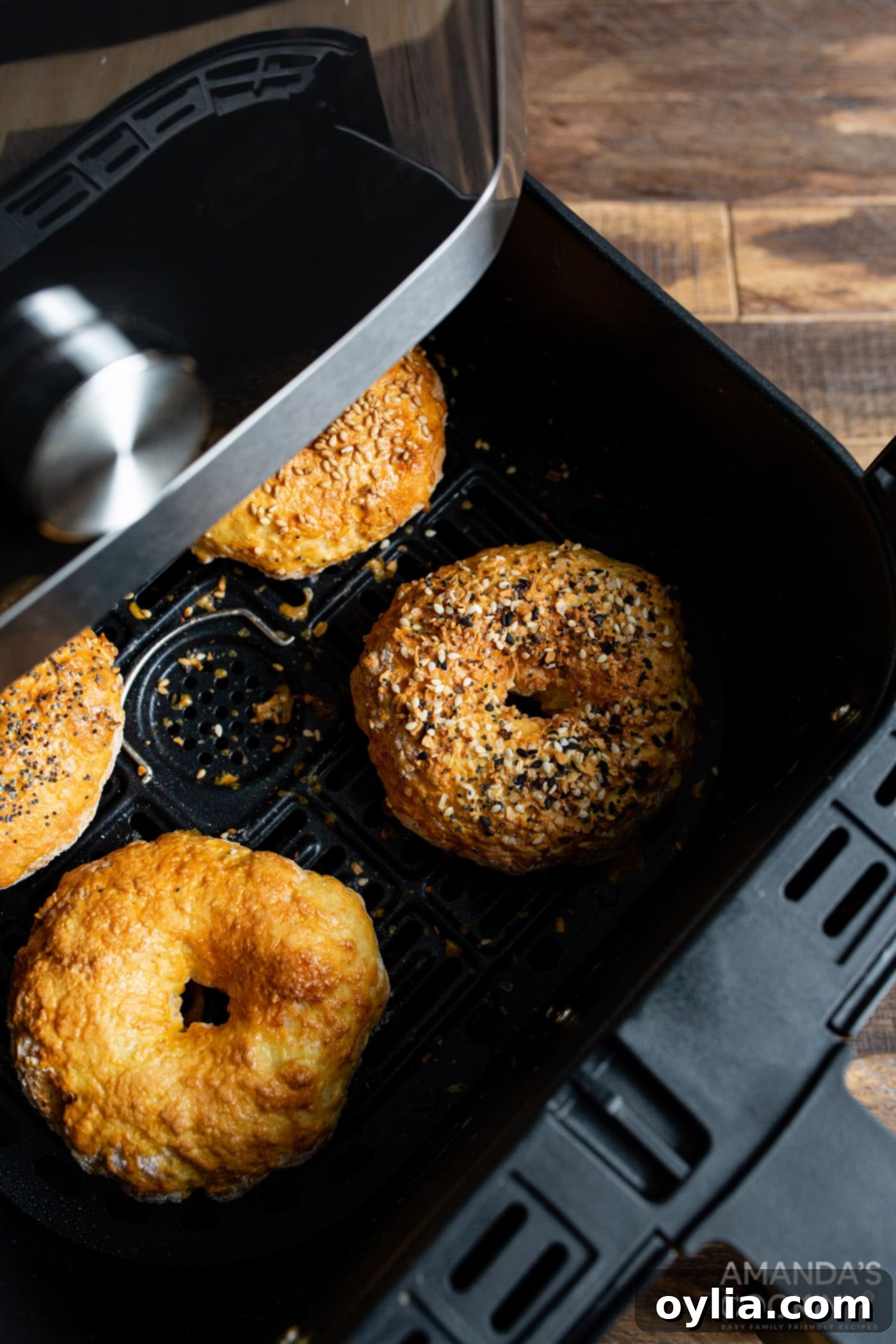 Golden brown bagels cooking in an air fryer basket.