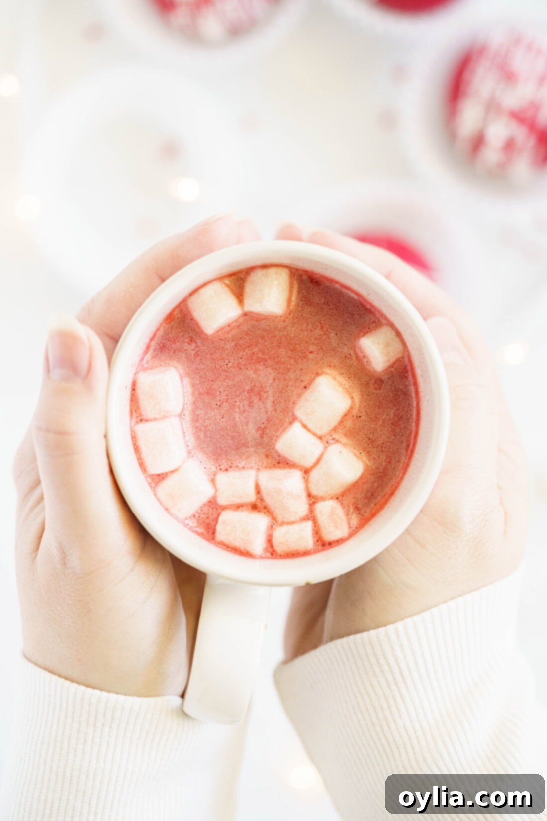 A close-up of a mug filled with creamy red velvet hot chocolate, topped with whipped cream and sprinkles, radiating warmth and comfort.