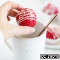 woman holding red velvet cocoa bomb over mug