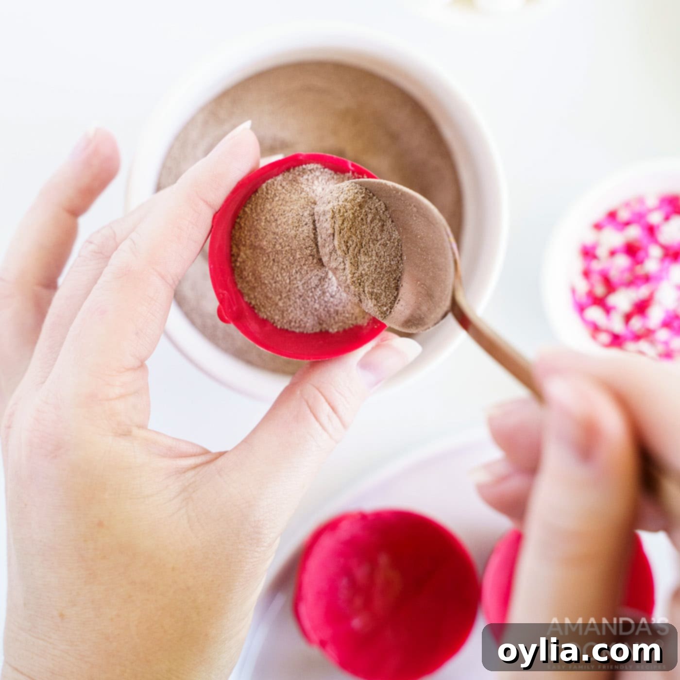 A candy half-sphere is being filled with hot cocoa mix, showing the generous amount of powder inside.