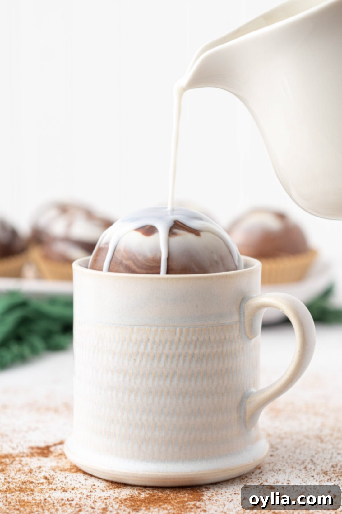 Warm milk being poured over a Marbled Mocha Hot Cocoa Bomb, causing it to melt and release its delicious contents.