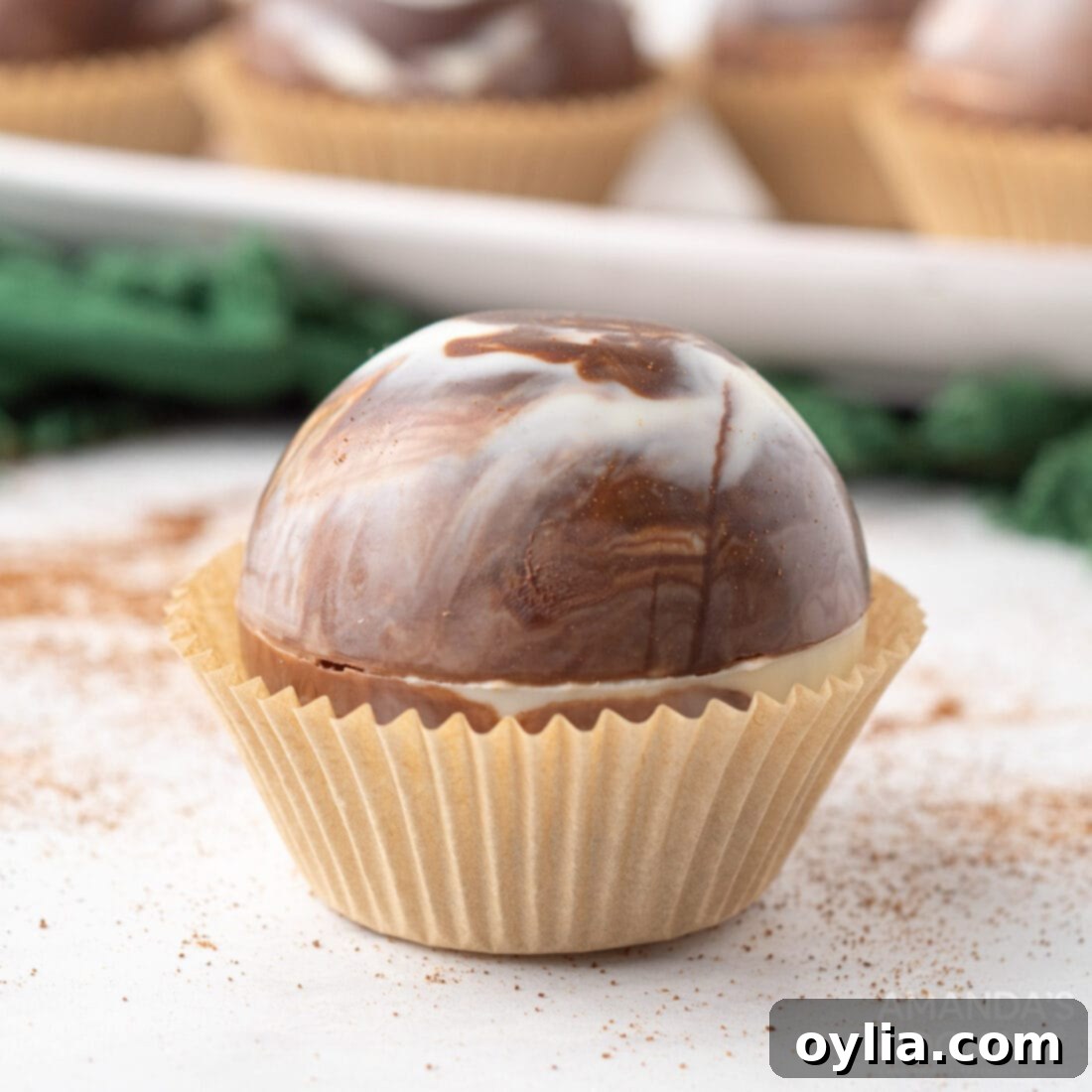 A single beautifully marbled mocha hot cocoa bomb rests in a silicone cupcake liner, showcasing its intricate design.