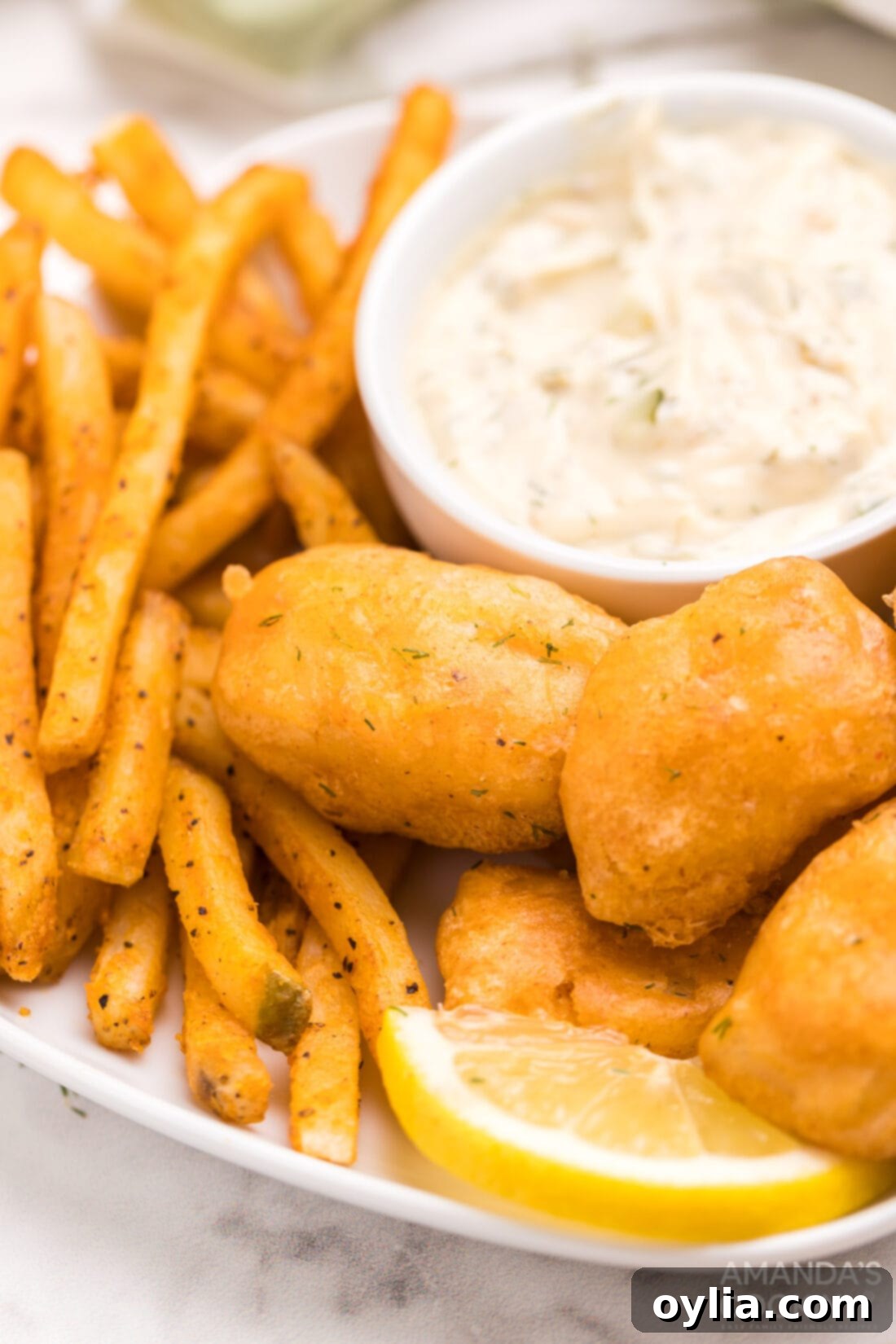 Crispy Beer Battered Fish and Chips on a plate with lemon and tartar sauce