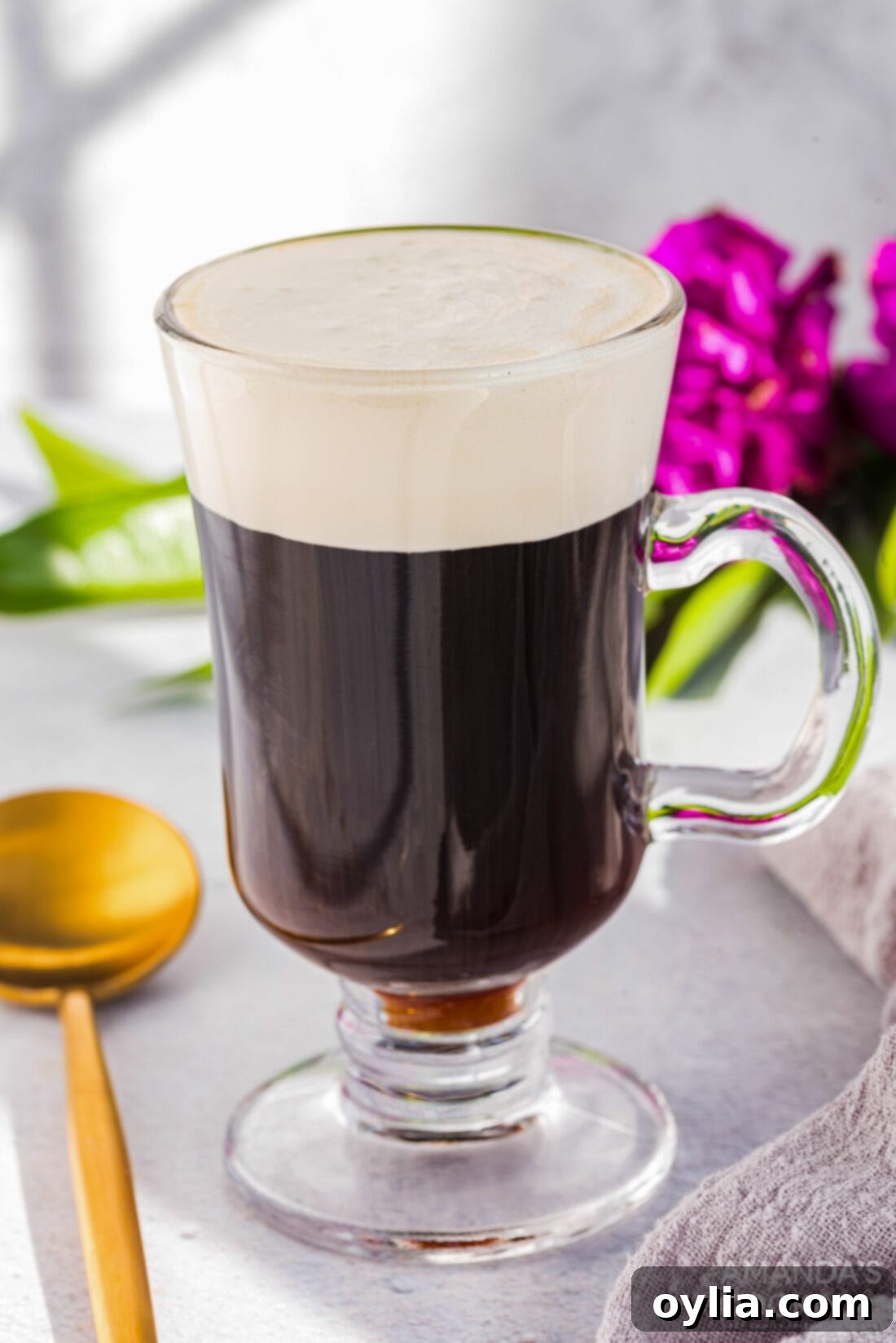 Another perspective of a glass mug of Irish coffee, highlighting its inviting warmth and luxurious cream topping.