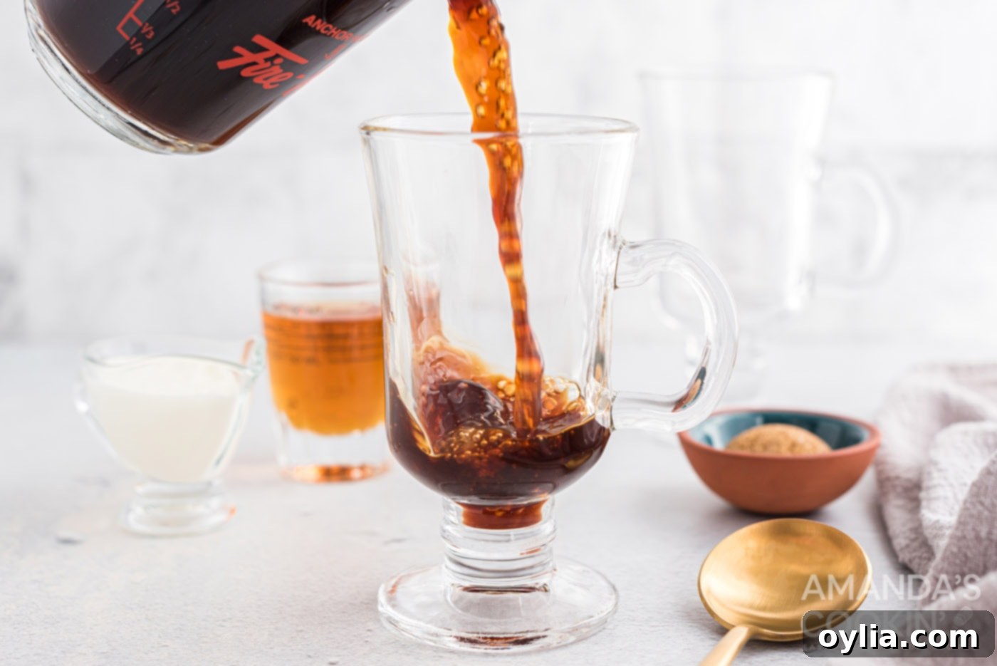 A close-up shot of hot, freshly brewed coffee being poured into a pre-warmed glass mug for Irish coffee.