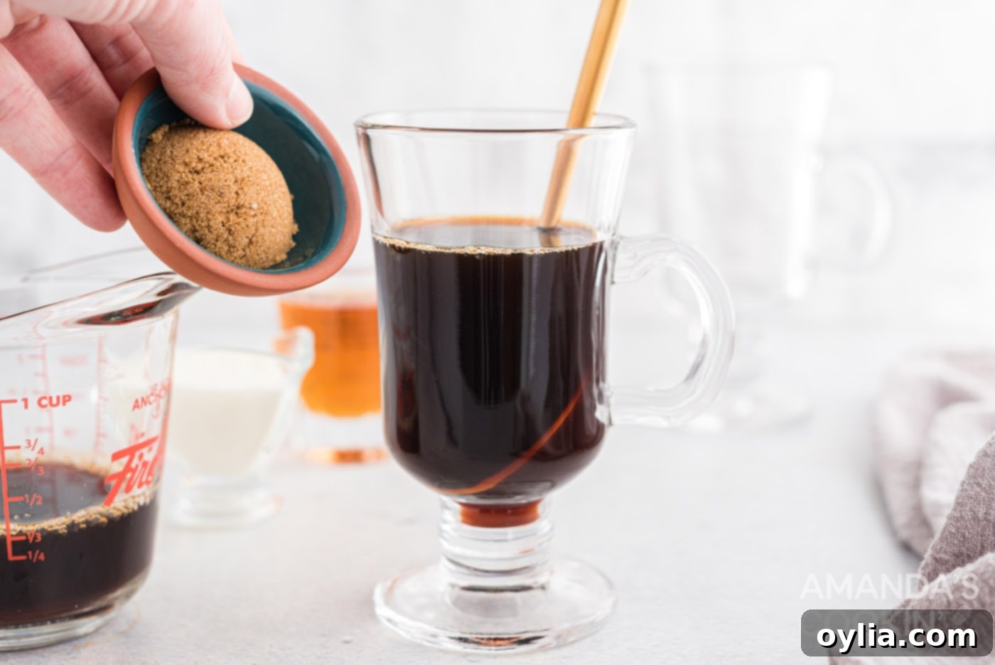 Brown sugar being carefully stirred into a mug of hot coffee, ensuring full dissolution.