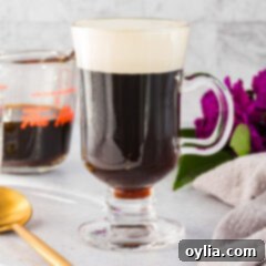 A charming close-up of a glass mug of Irish coffee, showcasing the perfect layer of cream and warm, dark coffee beneath.