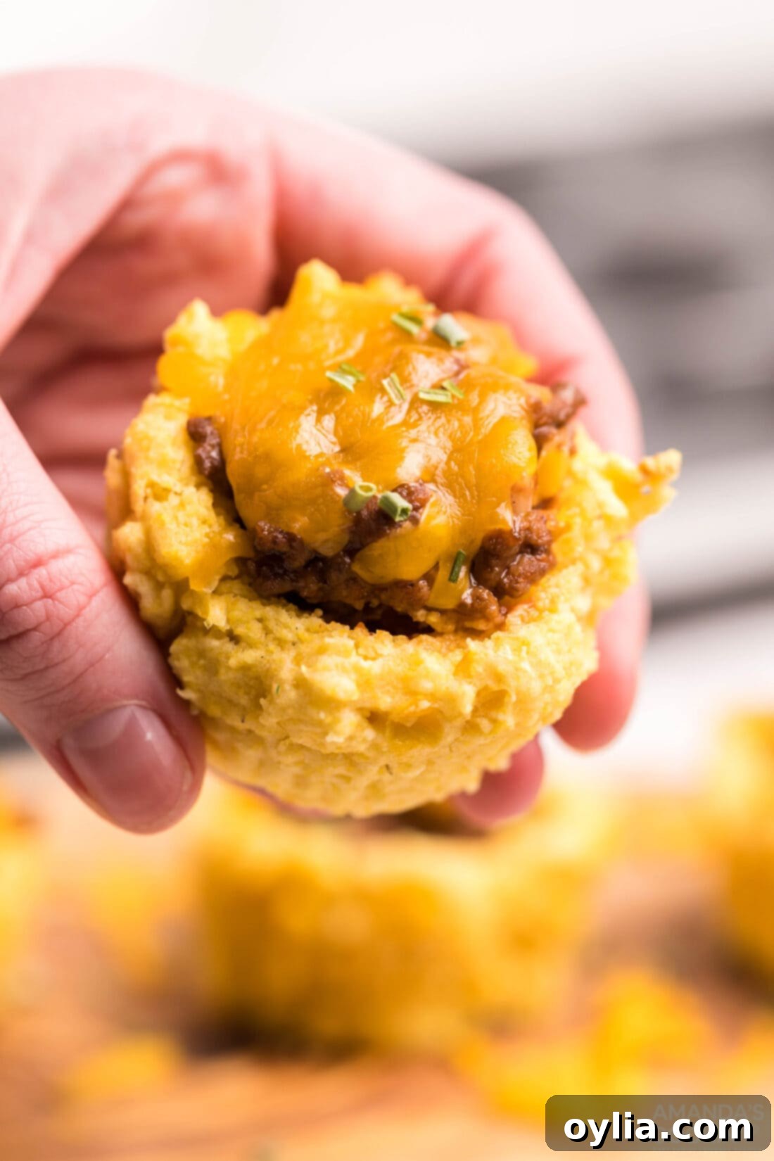Woman holding a Sloppy Joe Corn Muffin, showing its inviting presentation.