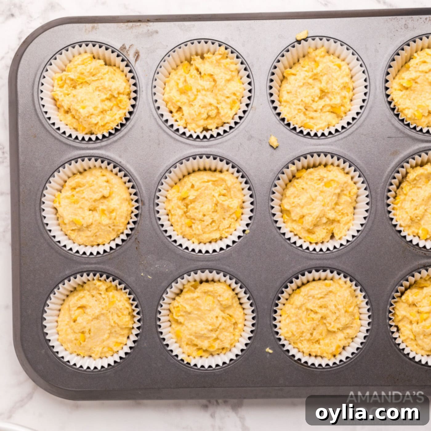 Cornbread muffin batter poured into a muffin pan, ready for baking.