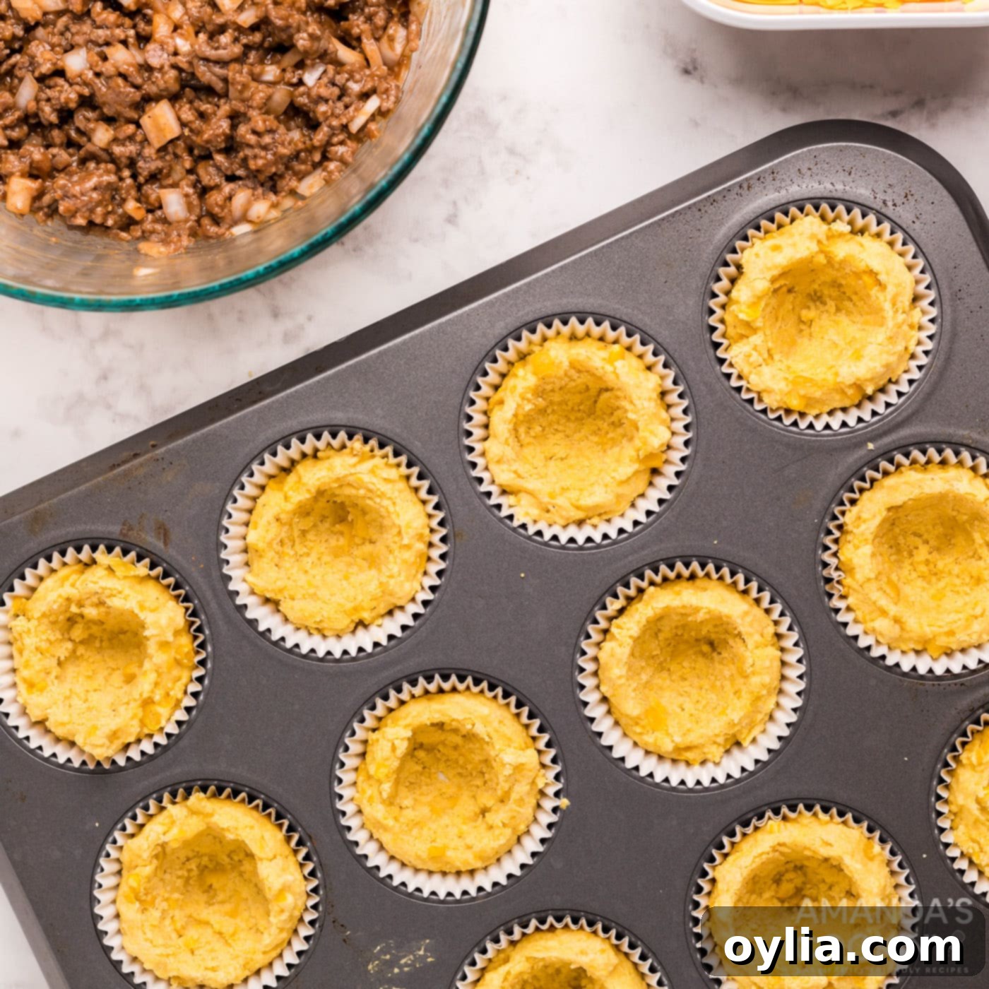 Center of cornbread removed in a muffin tin to create a well for the sloppy joe.