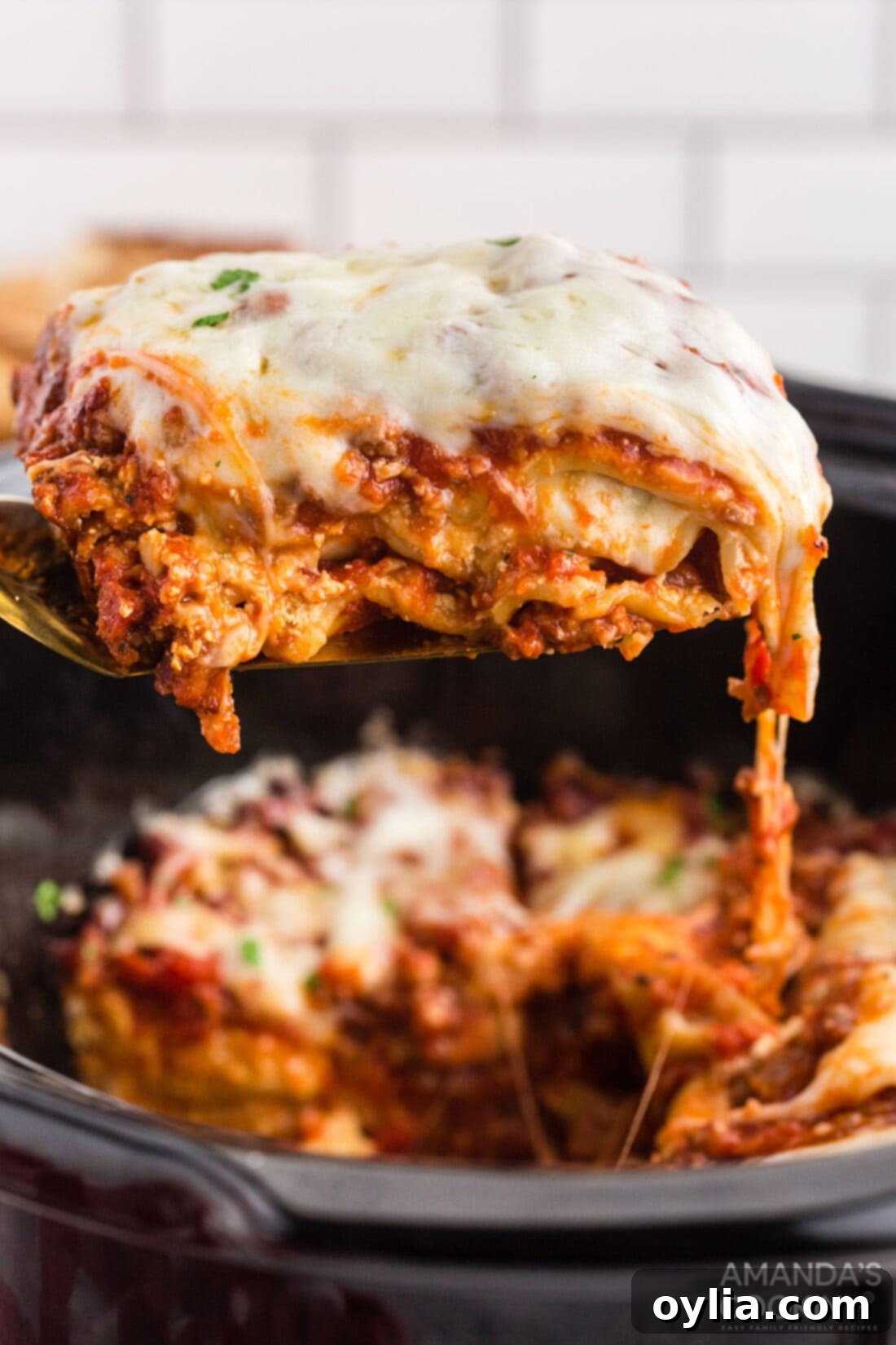 Set It and Forget It Lasagna 3 A serving of hot, bubbly crockpot lasagna being lifted from the slow cooker with a spatula, showcasing its cheesy layers and perfect tenderness.