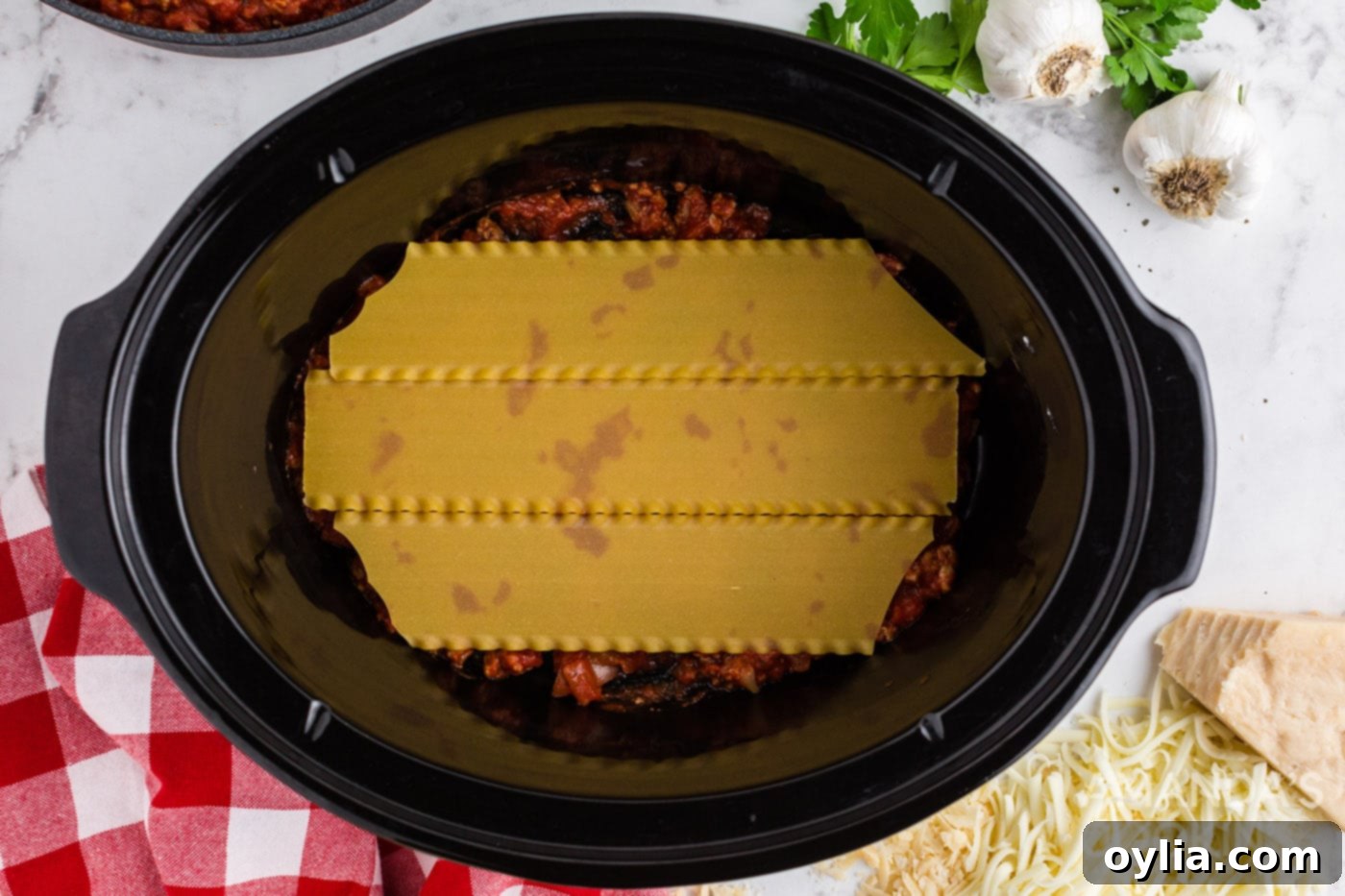 Set It and Forget It Lasagna 8 First layer of uncooked lasagna noodles placed over the meat sauce in the crockpot.