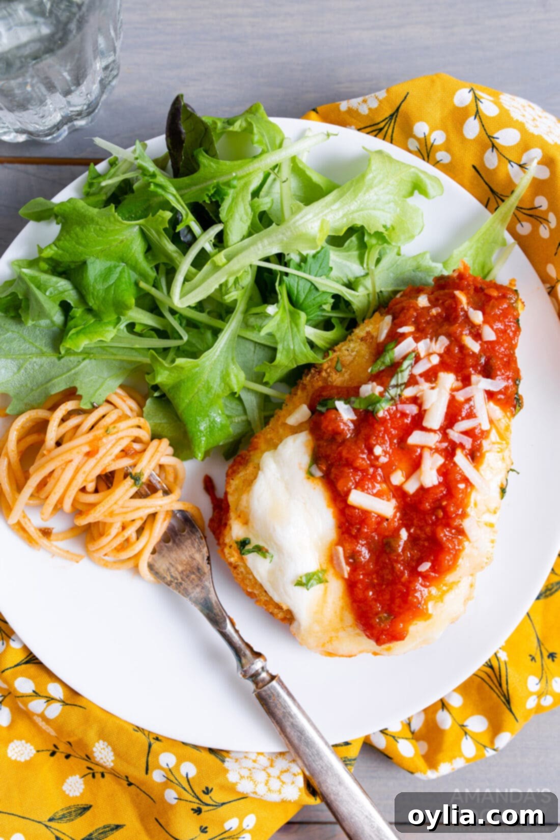 Crispy Air Fryer Chicken Parmesan 2 Air fryer chicken parmesan served on a plate with a fresh green salad, highlighting its golden-brown crispness and melted cheese.