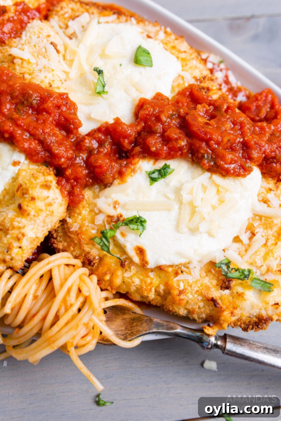Crispy Air Fryer Chicken Parmesan 12 Air fryer chicken parmesan served on a plate with spaghetti pasta and marinara sauce, garnished with fresh basil.