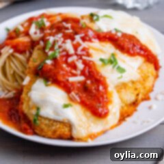 Crispy Air Fryer Chicken Parmesan 13 A plate featuring a crispy, saucy air fryer chicken parmesan cutlet, topped with melted cheese and fresh basil.