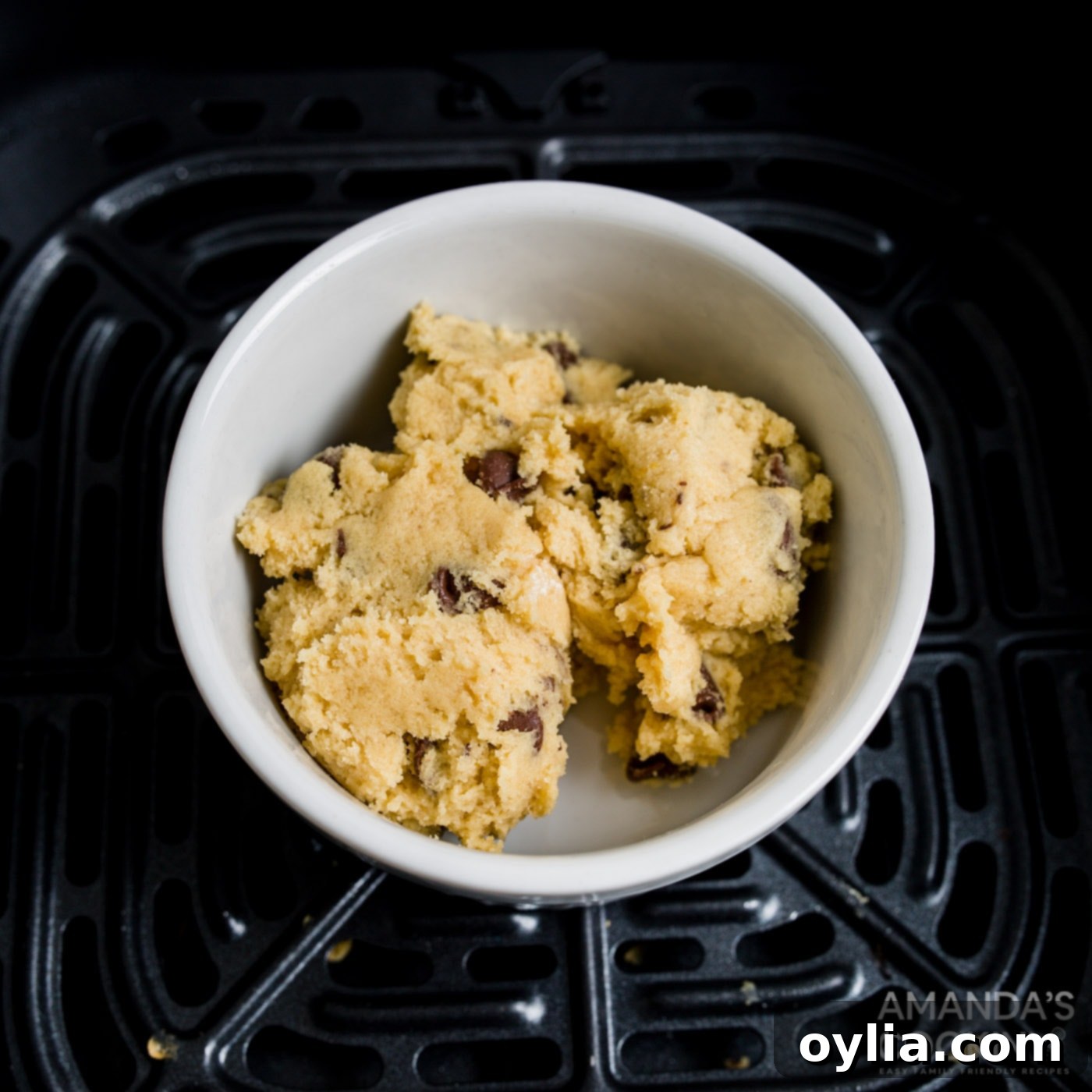 Cookie dough scooped into a white ramekin, topped with extra chocolate chips.