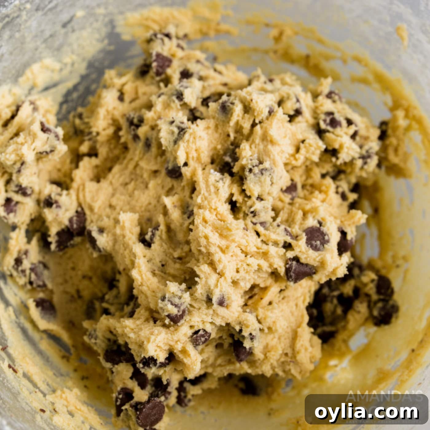 Chocolate chip cookie dough with visible chocolate chips in a mixing bowl, ready for baking.