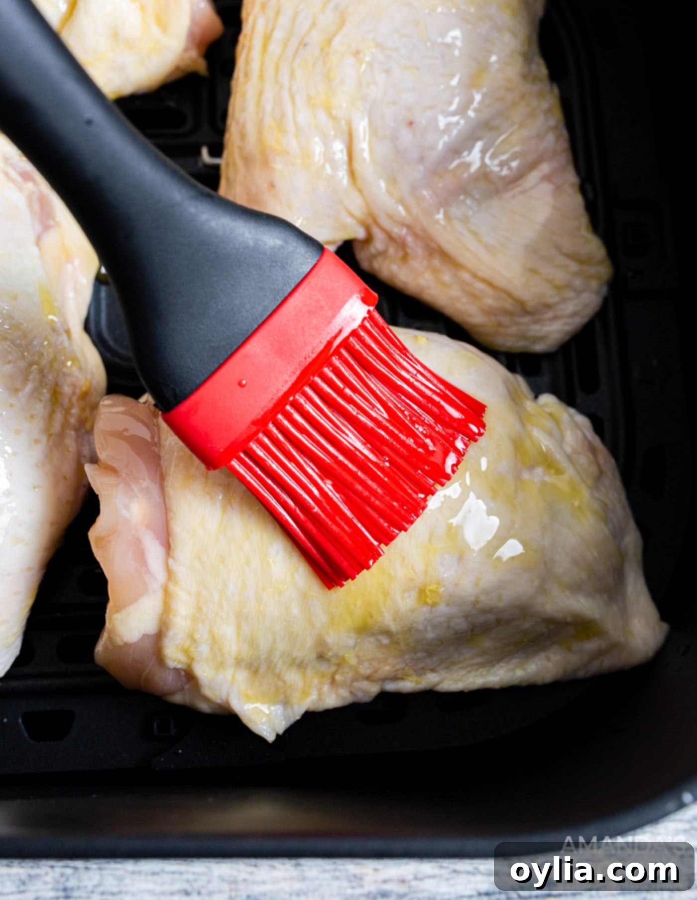 brushing chicken thighs with olive oil before seasoning