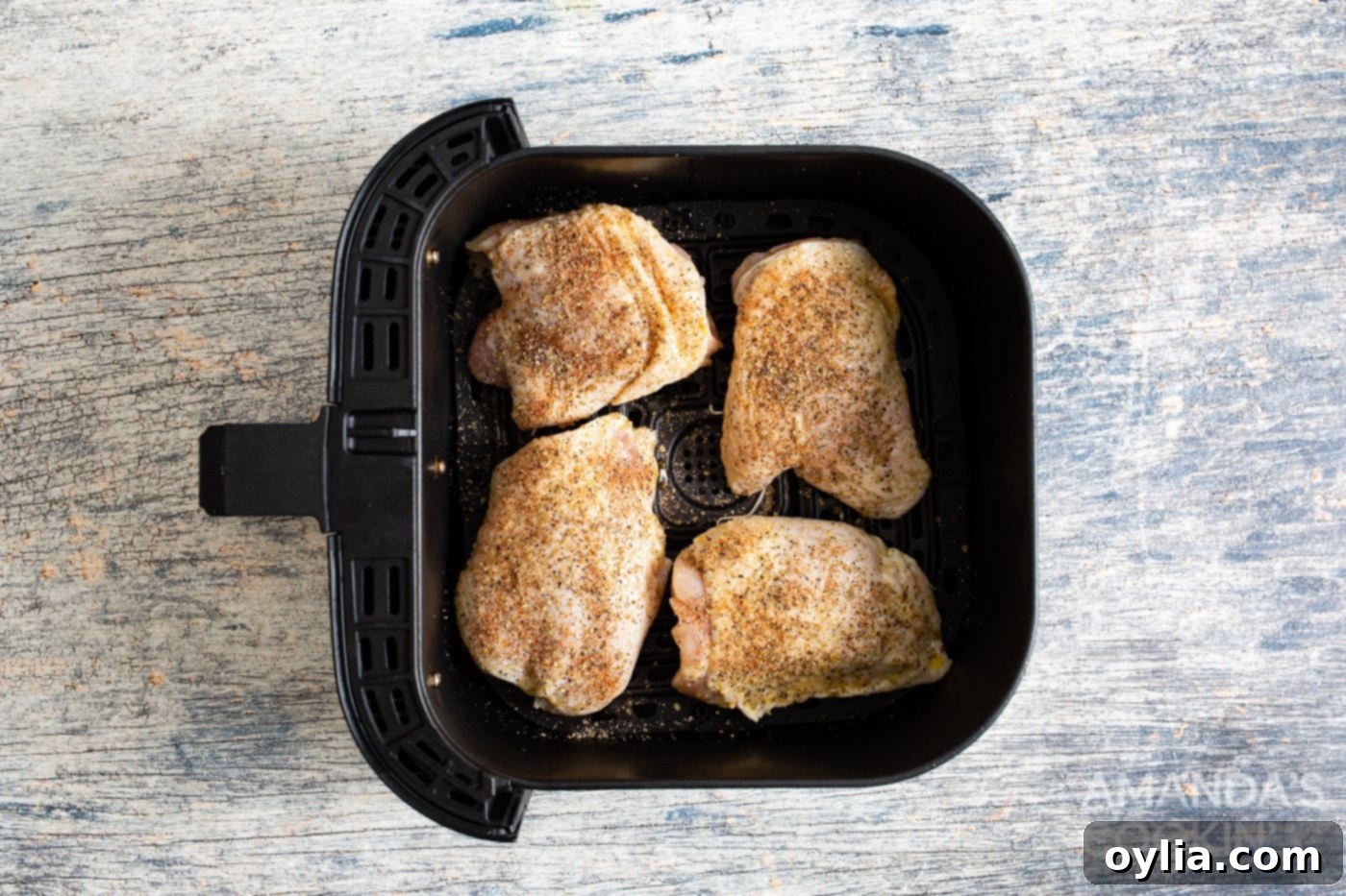 chicken thighs placed skin side down in an air fryer basket