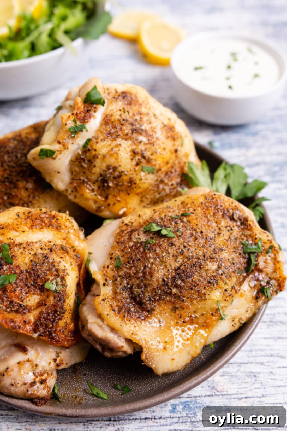 Crispy Air Fryer Chicken Thighs 9 air fried chicken thighs on a plate, garnished with fresh herbs