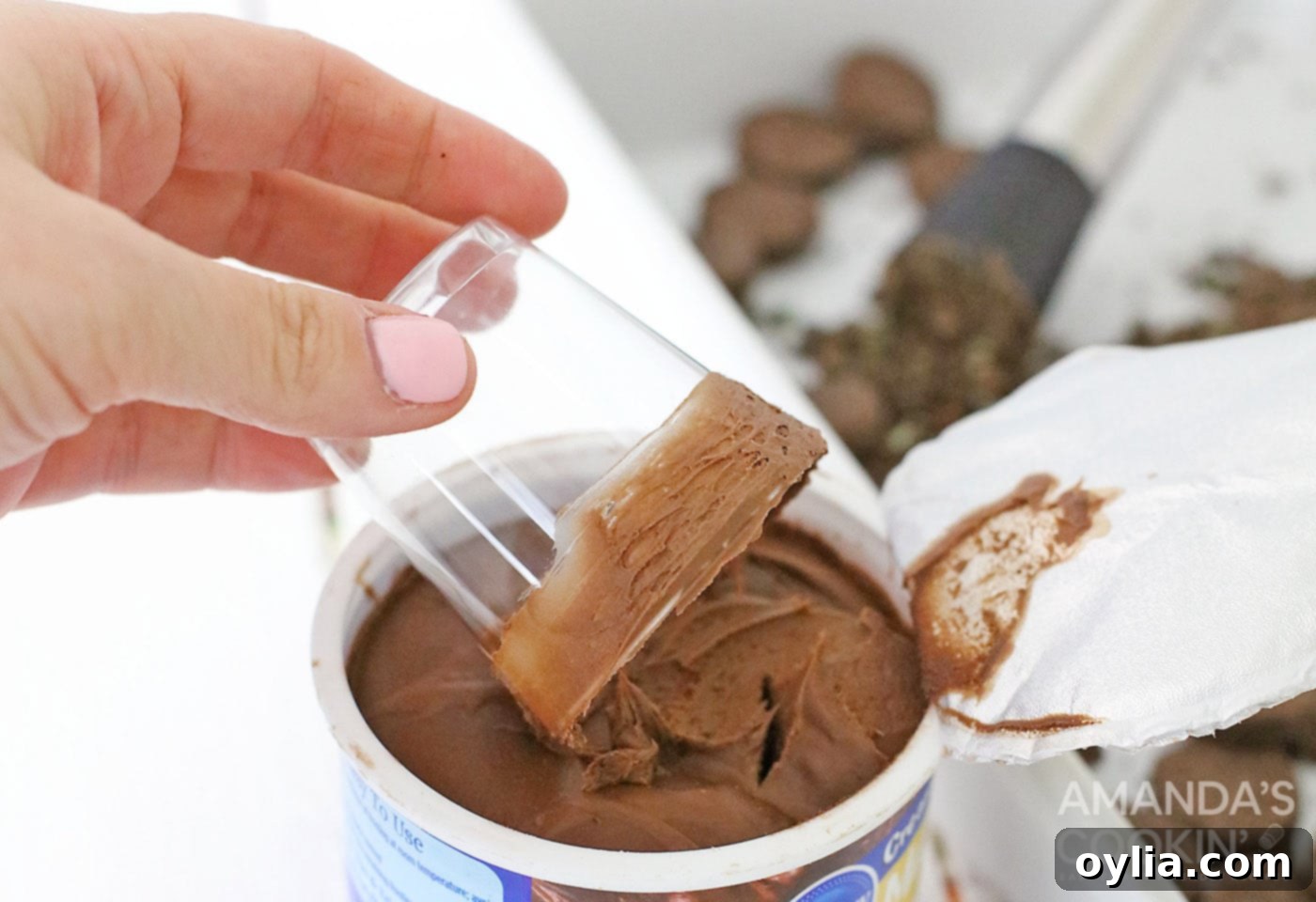 Image illustrating the process of coating the rim of a shot glass with chocolate frosting.