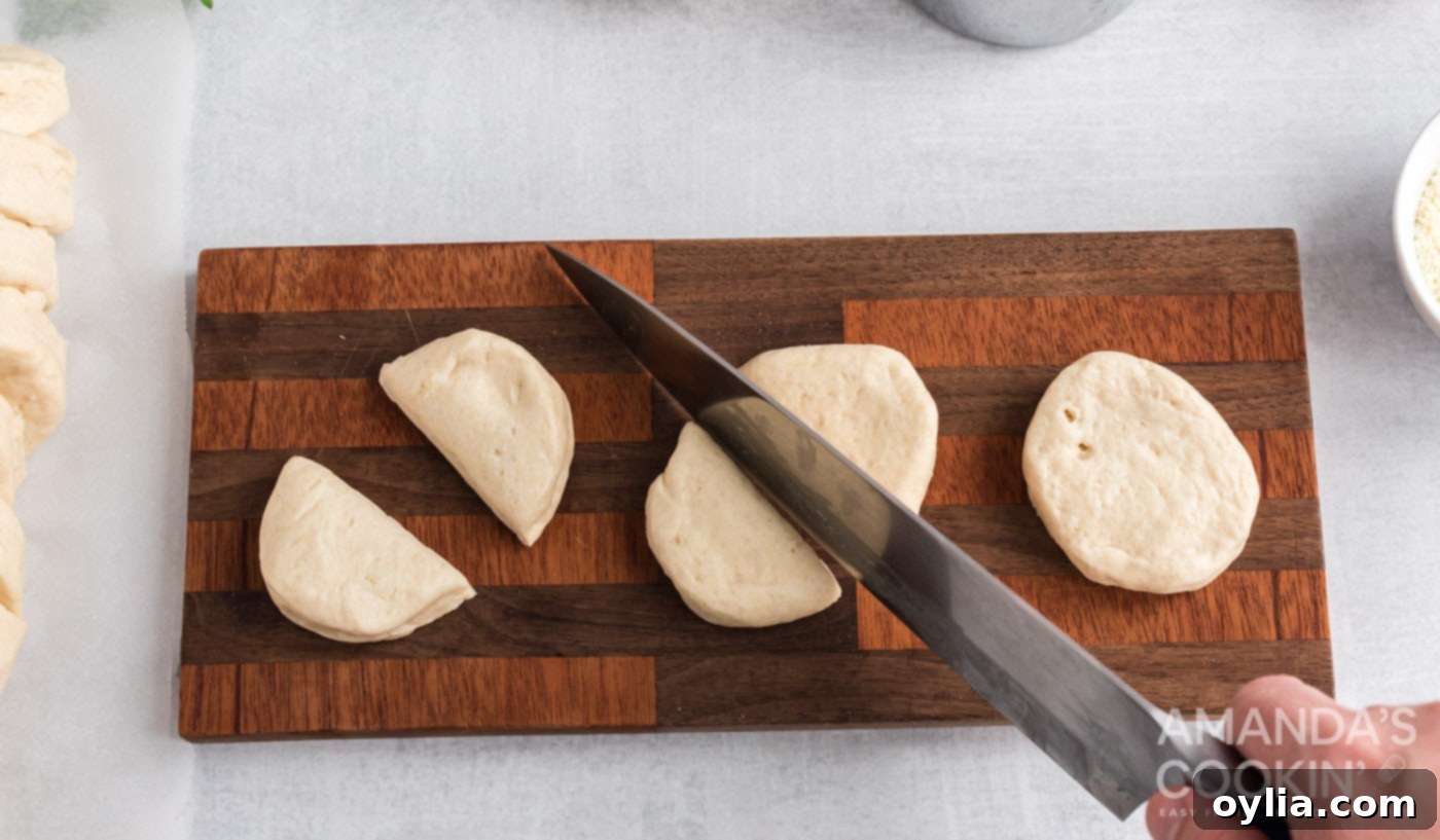 Biscuits being cut into fourths on a cutting board, ready to be rolled into balls.