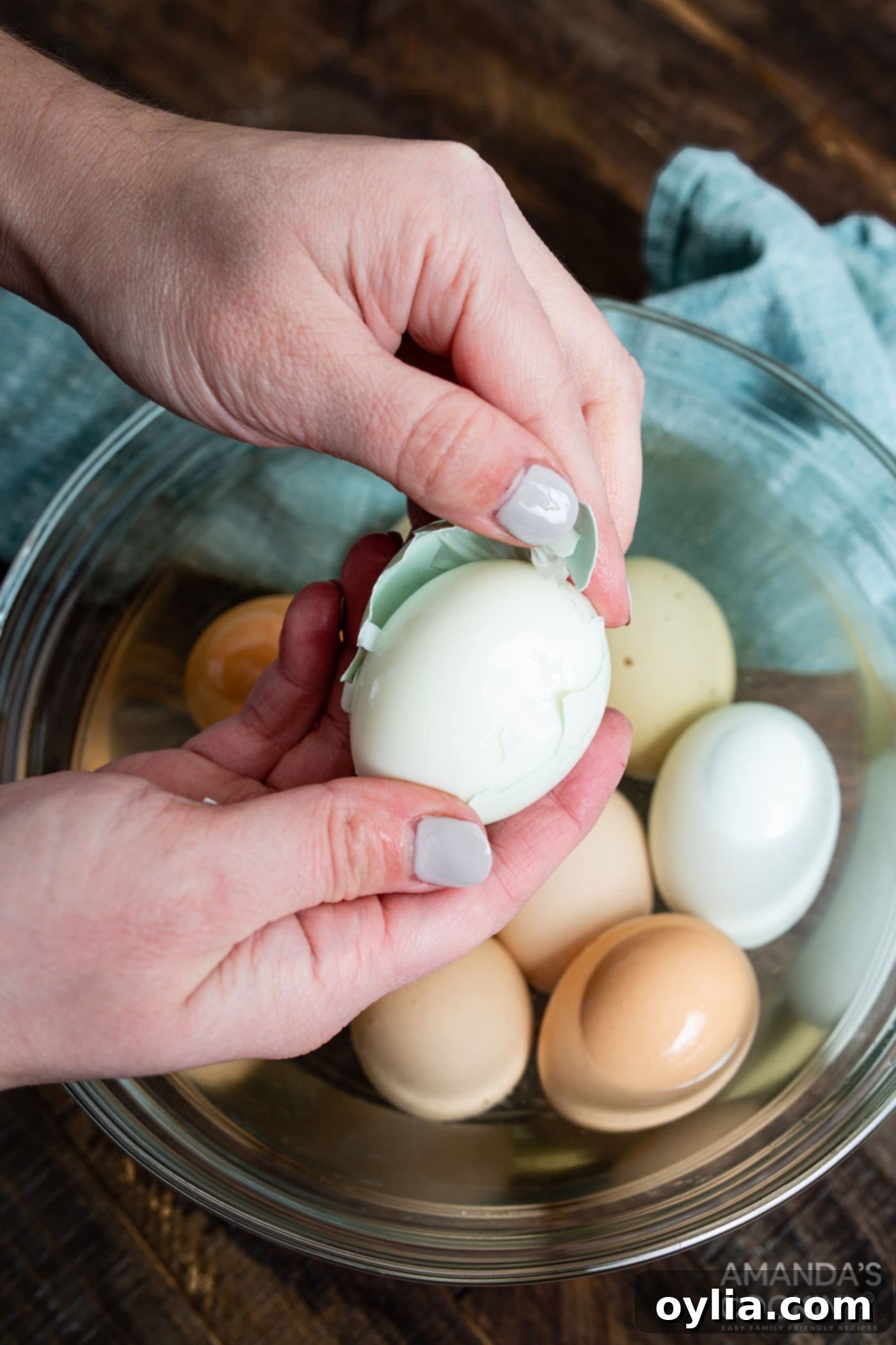 A hand gently peeling an air fryer hard boiled egg, revealing a smooth, cooked white beneath the shell.