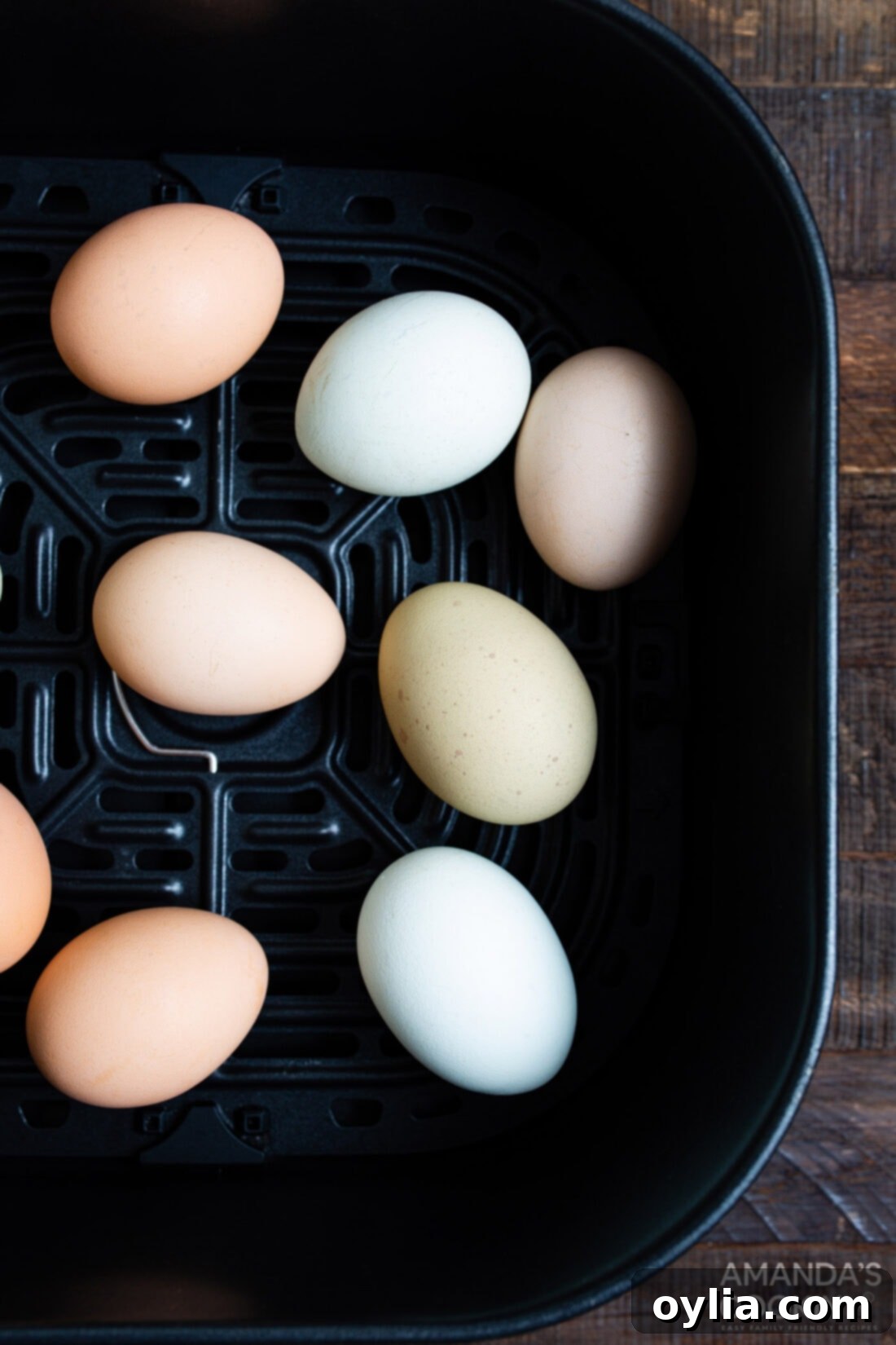 Your Go To Air Fryer Hard Boiled Eggs 8 A basket of an air fryer containing several air-fried hard boiled eggs, ready to be cooled and peeled.