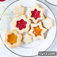 Festive Linzer Sandwich Cookies 11 A close-up of a stack of jam-filled Linzer cookies, showcasing their intricate cut-out and powdered sugar dusting, ready to be served.