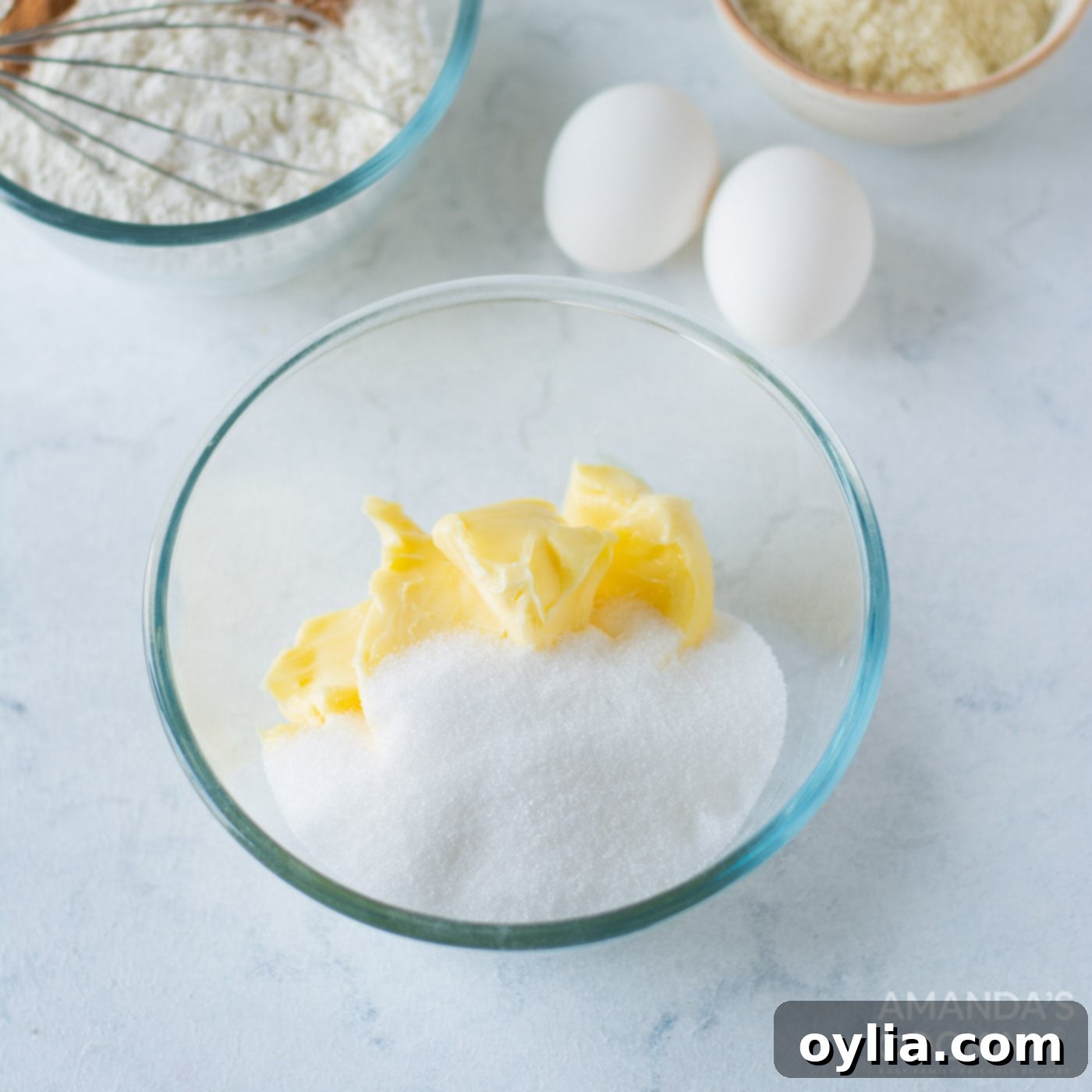 Softened unsalted butter and granulated sugar being creamed together in a large mixing bowl until light, fluffy, and perfectly combined.