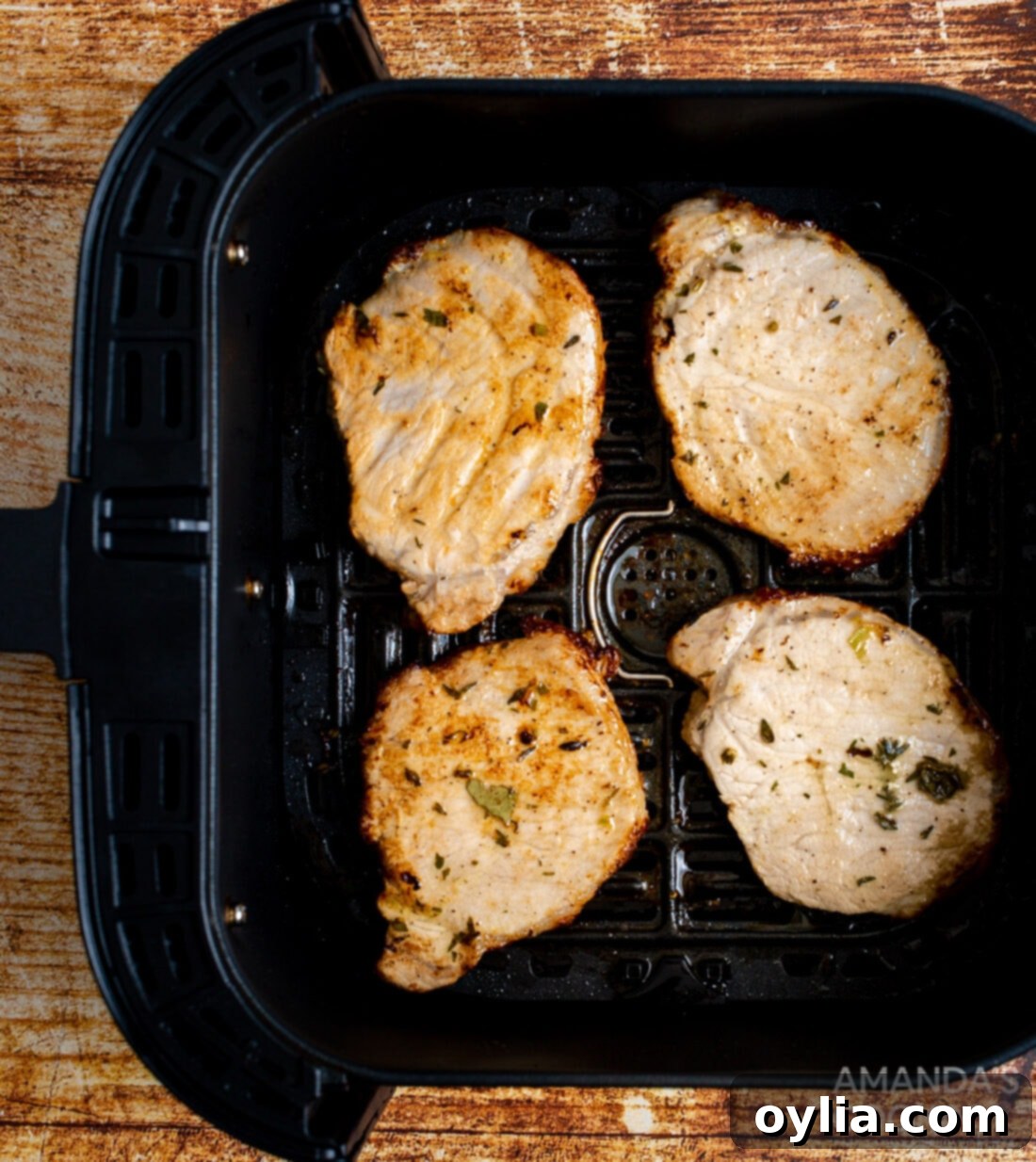 Crispy Air Fryer Pork Chops 3 pork chops in an air fryer basket