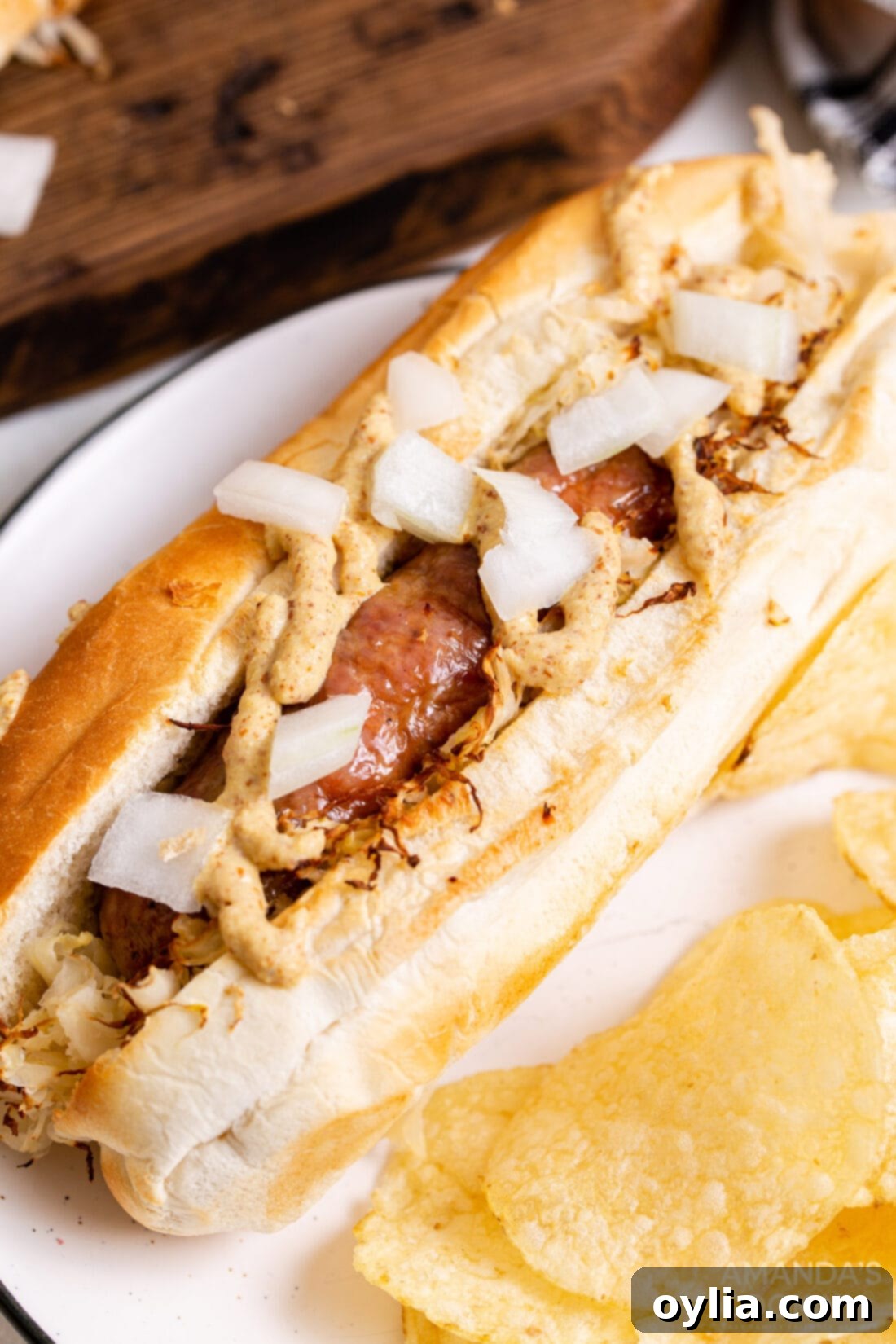 Perfect Air Fryer Bratwurst 9 air fryer bratwurst on a bun with sauerkraut, mustard and onion