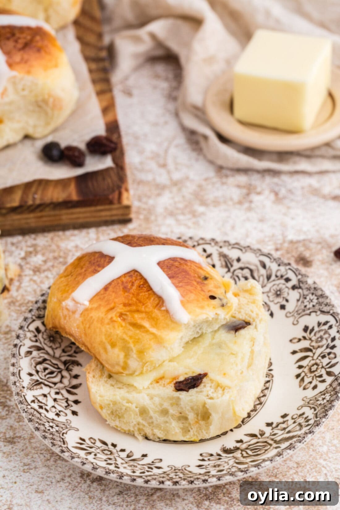 A sliced Hot Cross Bun on a plate, showing its soft interior and fruit pieces