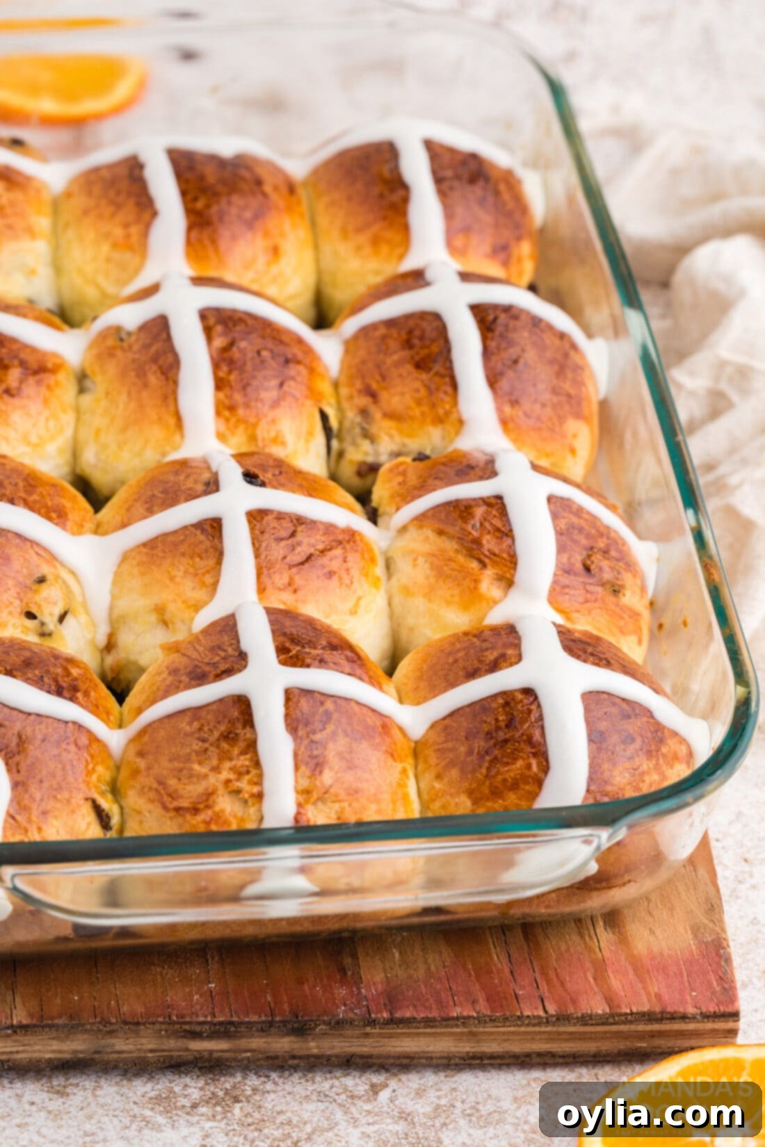 A glass pan filled with freshly baked and iced hot cross buns