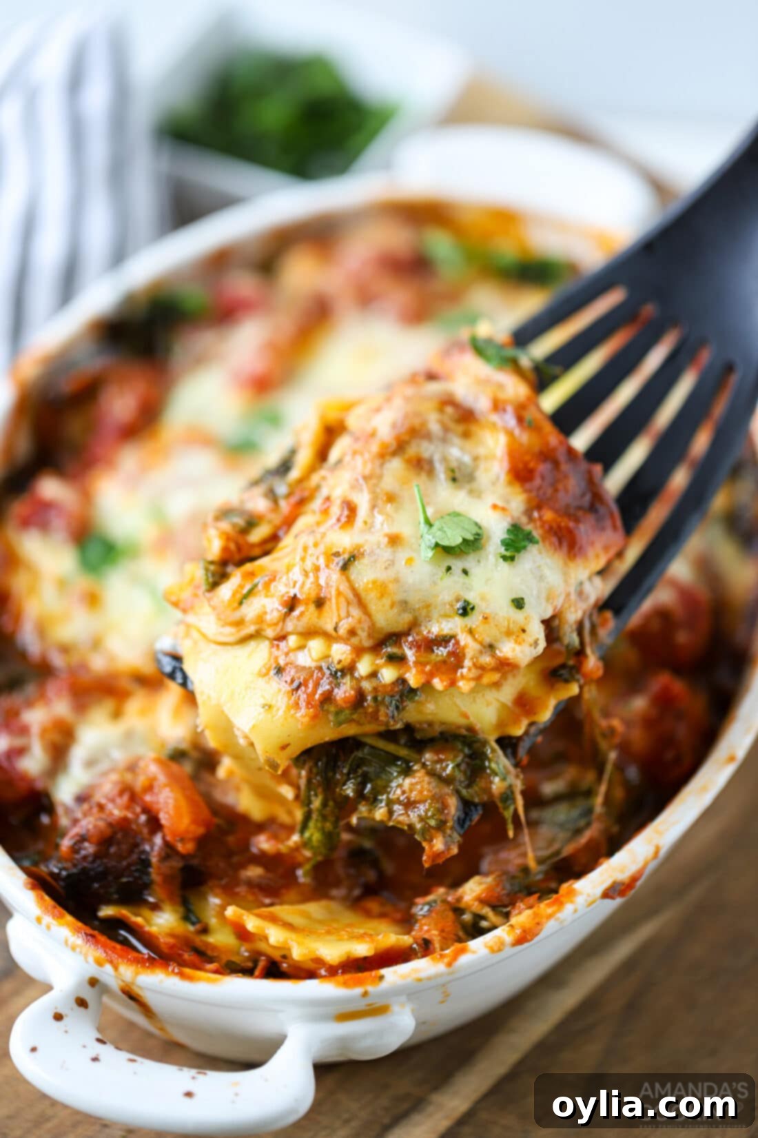 pinterest image with text: Cheesy Ravioli Lasagna, Layers of marinara, ravioli, mozzarella, baby spinach, and sausage baked to a bubbly golden brown.