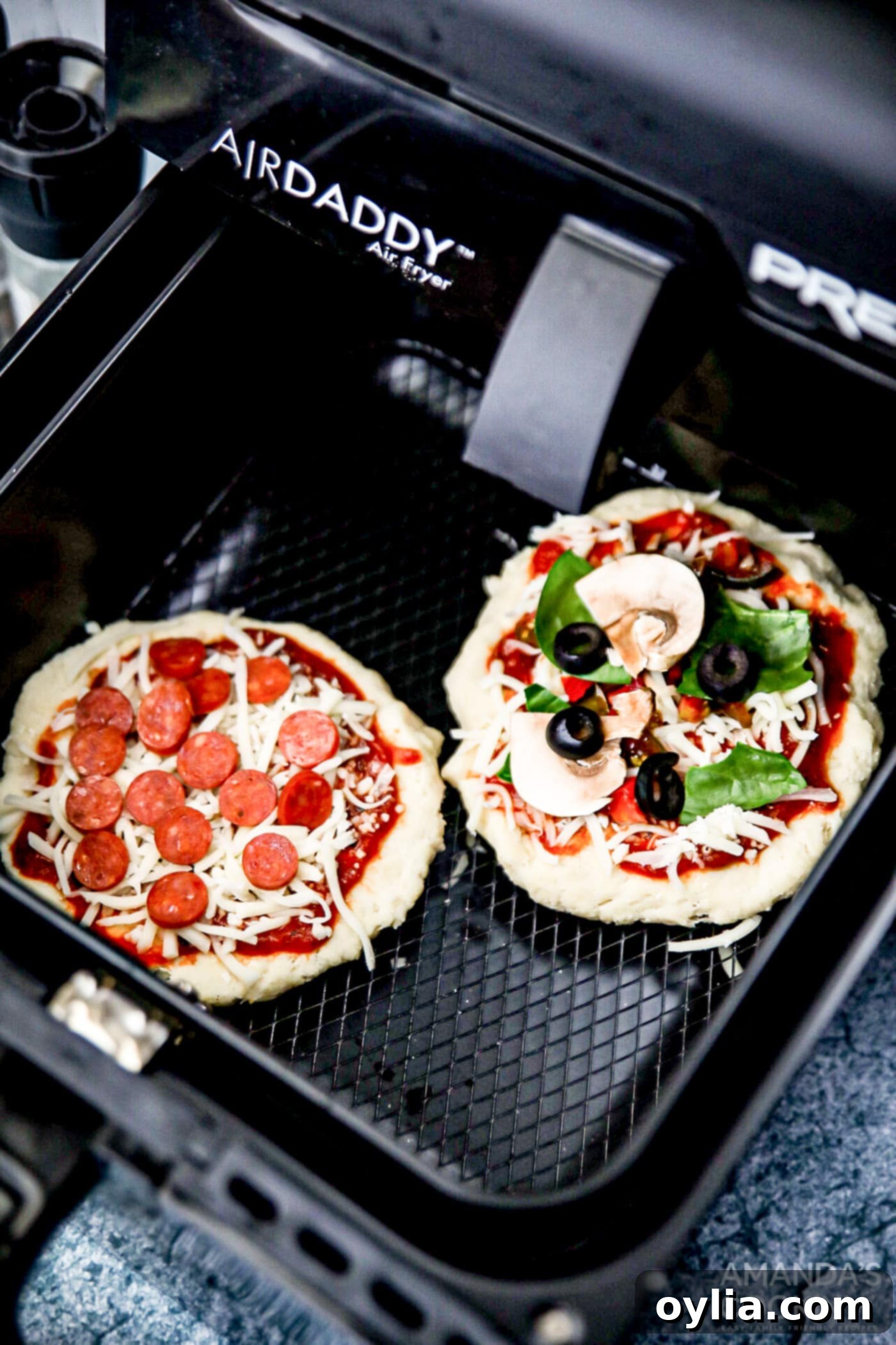 uncooked pizza in air fryer with various toppings before cooking