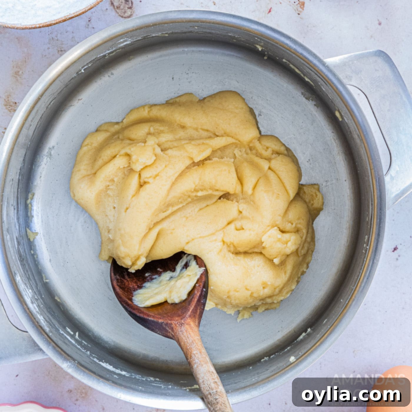 Stirring churro dough vigorously with a wooden spoon in a saucepan until it forms a smooth ball.