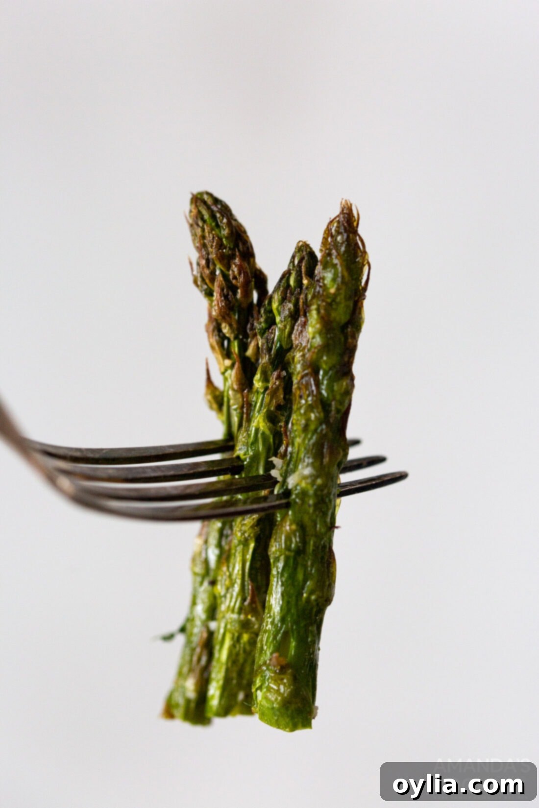 close-up of a fork holding a piece of air-fried asparagus