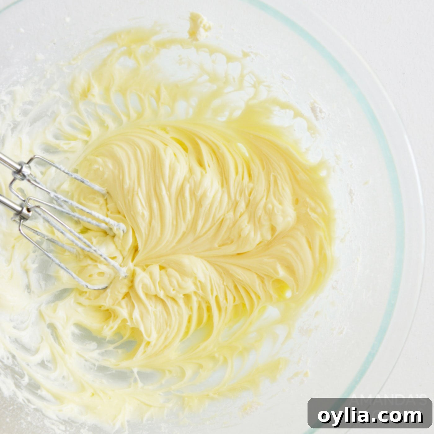 beating cream cheese frosting with a handheld mixer until smooth