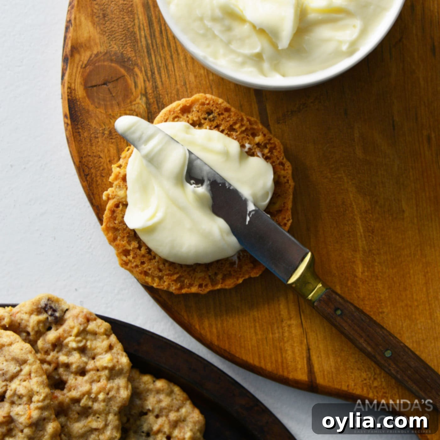 spreading cream cheese frosting onto cookie with a butter knife for assembly